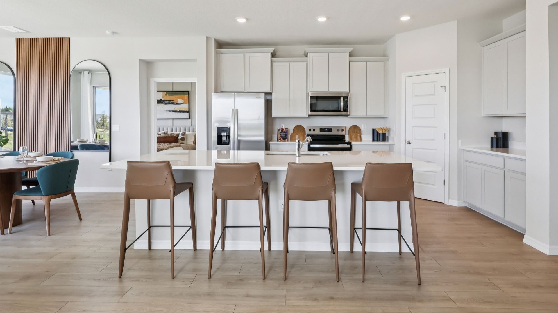 Kitchen with island seating, quartz counters, spacious pantry and stainless steel appliances.