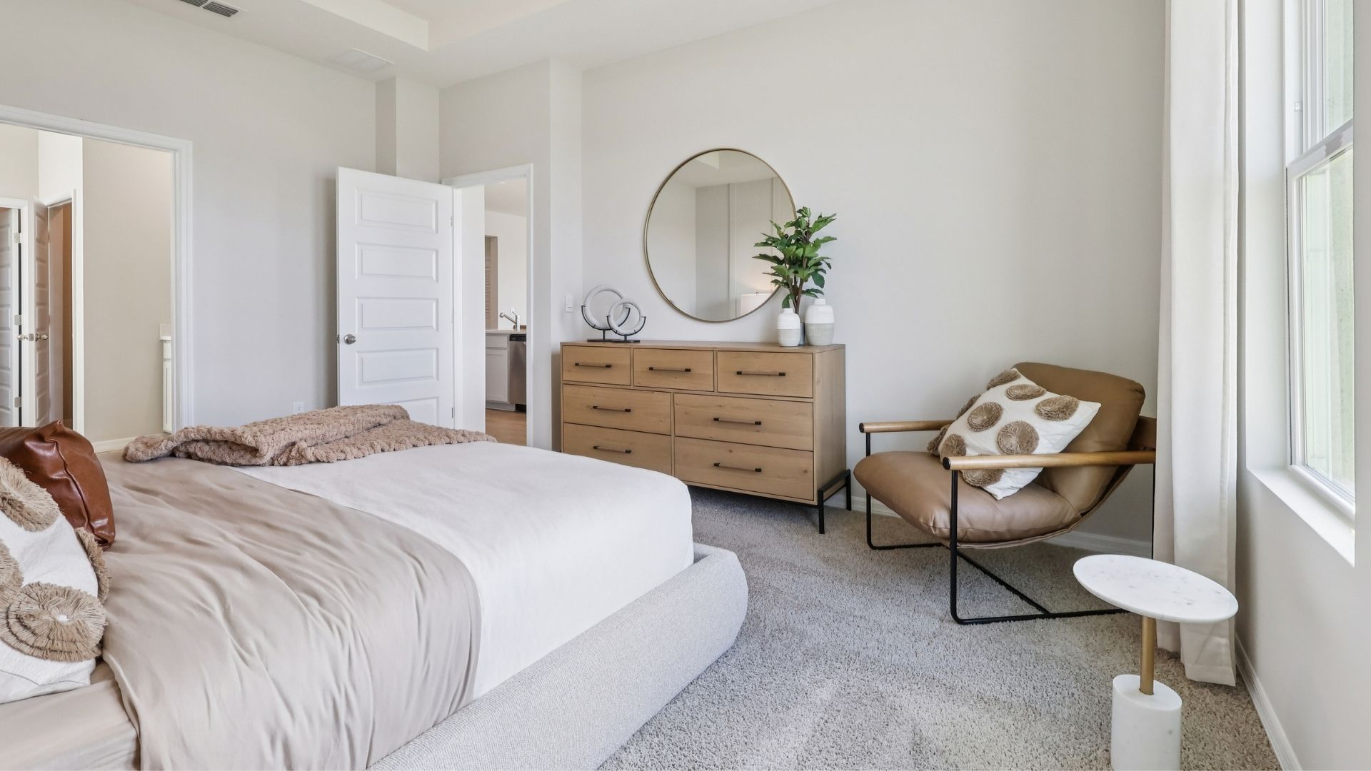 Spacious primary bedroom with king size bed, carpet flooring, natural lighting.