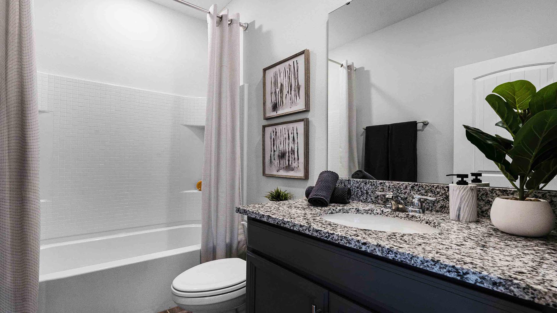 Guest bathroom with single vanity with granite countertops, large mirror, toilet and shower.