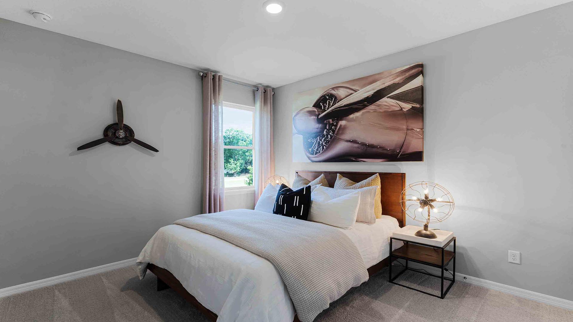 Guest bedroom with bed, nighstand, desk, and natural lighting.