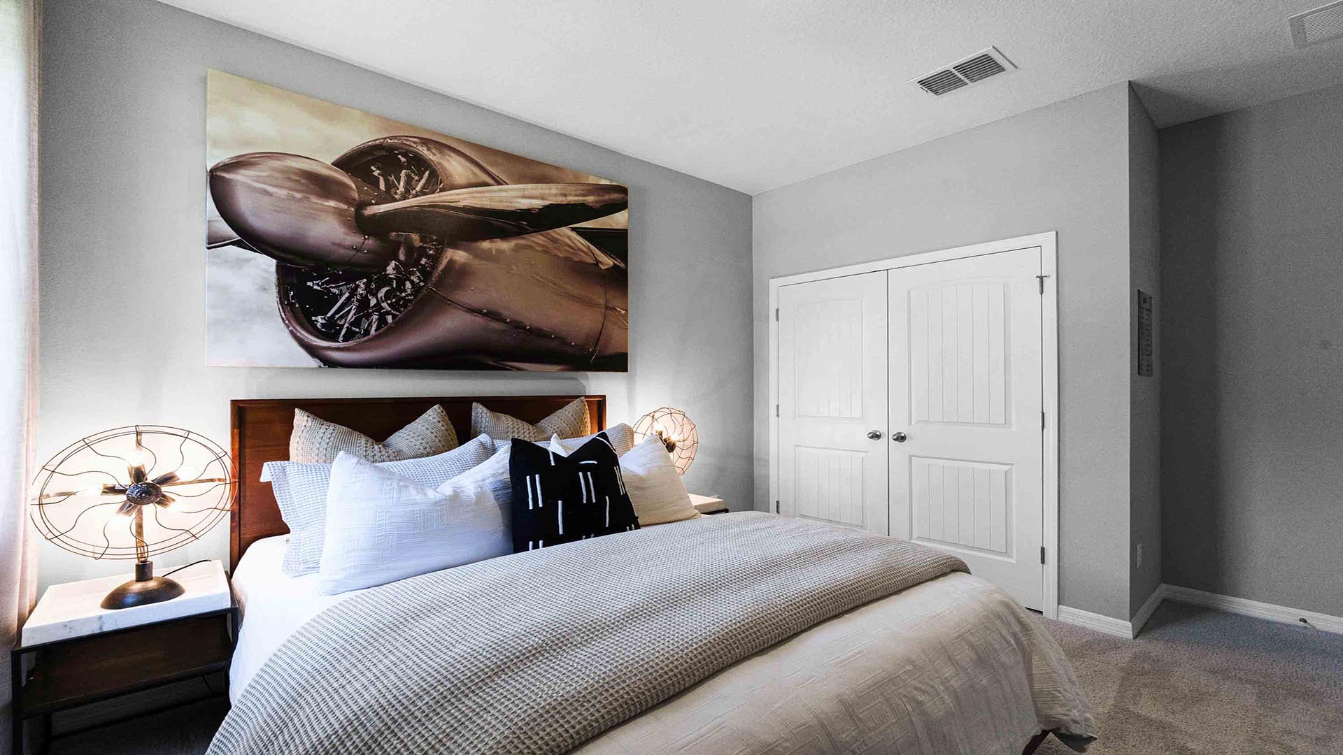 Guest bedroom with bed, nighstand and natural lighting and spacious closet.