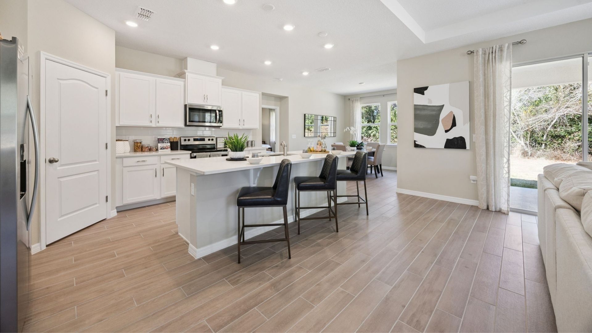 Kitchen with island seating, quartz counters, spacous pantry and stainless steel appliances.