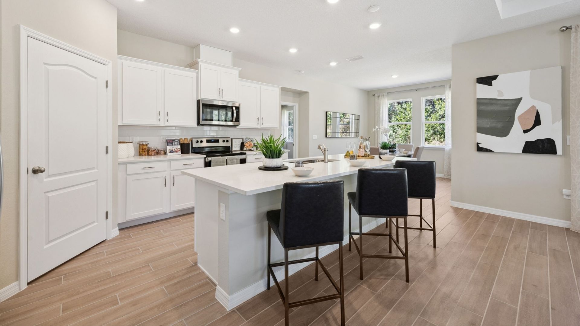 Kitchen with island seating, quartz counters, spacous pantry and stainless steel appliances.