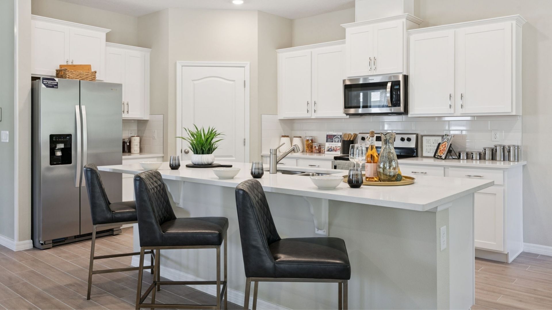 Kitchen with island seating, quartz counters, spacous pantry and stainless steel appliances.