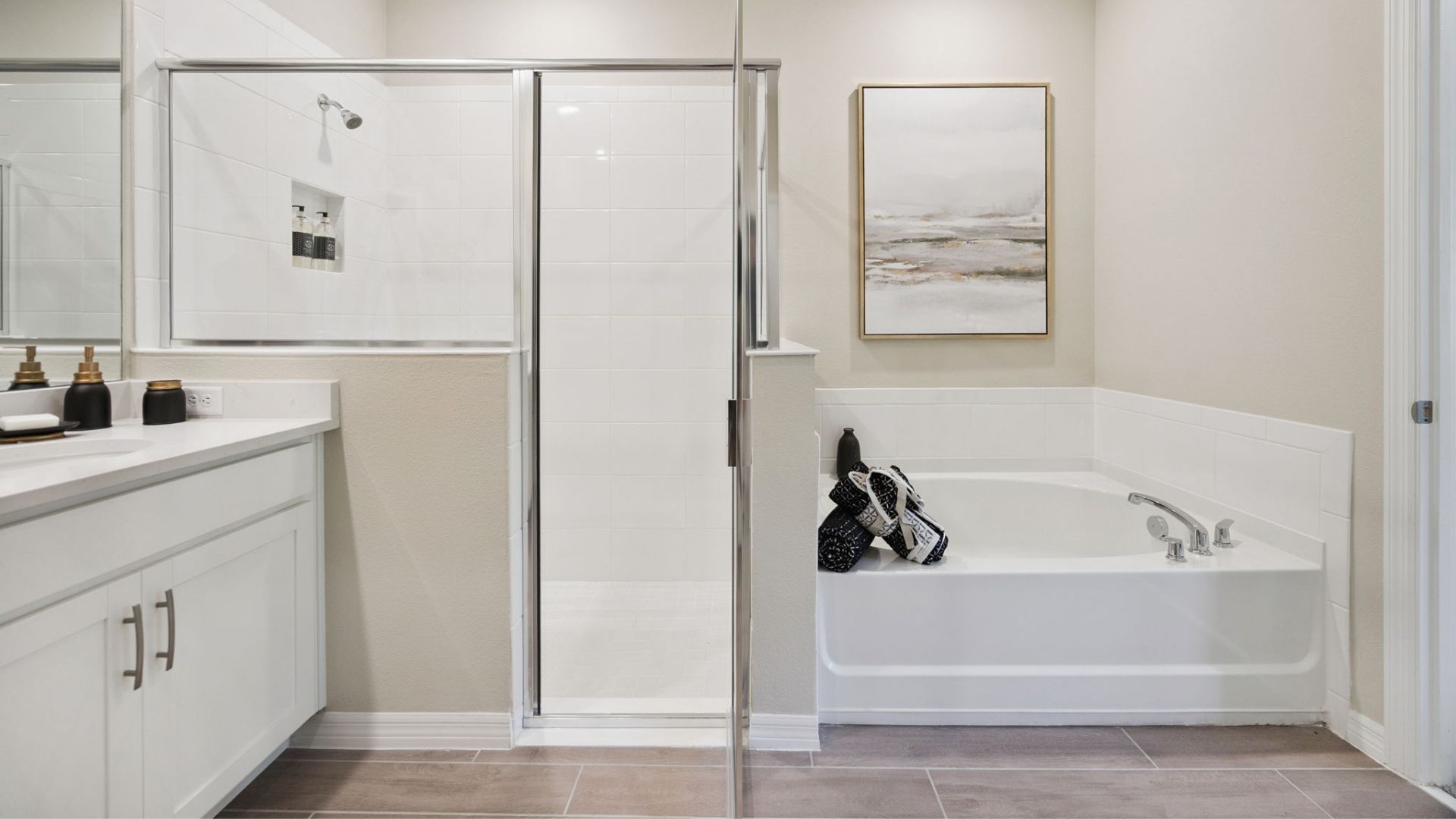 Modern bathroom with double vanity granite countertops, with cabinet and large wall mirror showing access to primary bedroom.