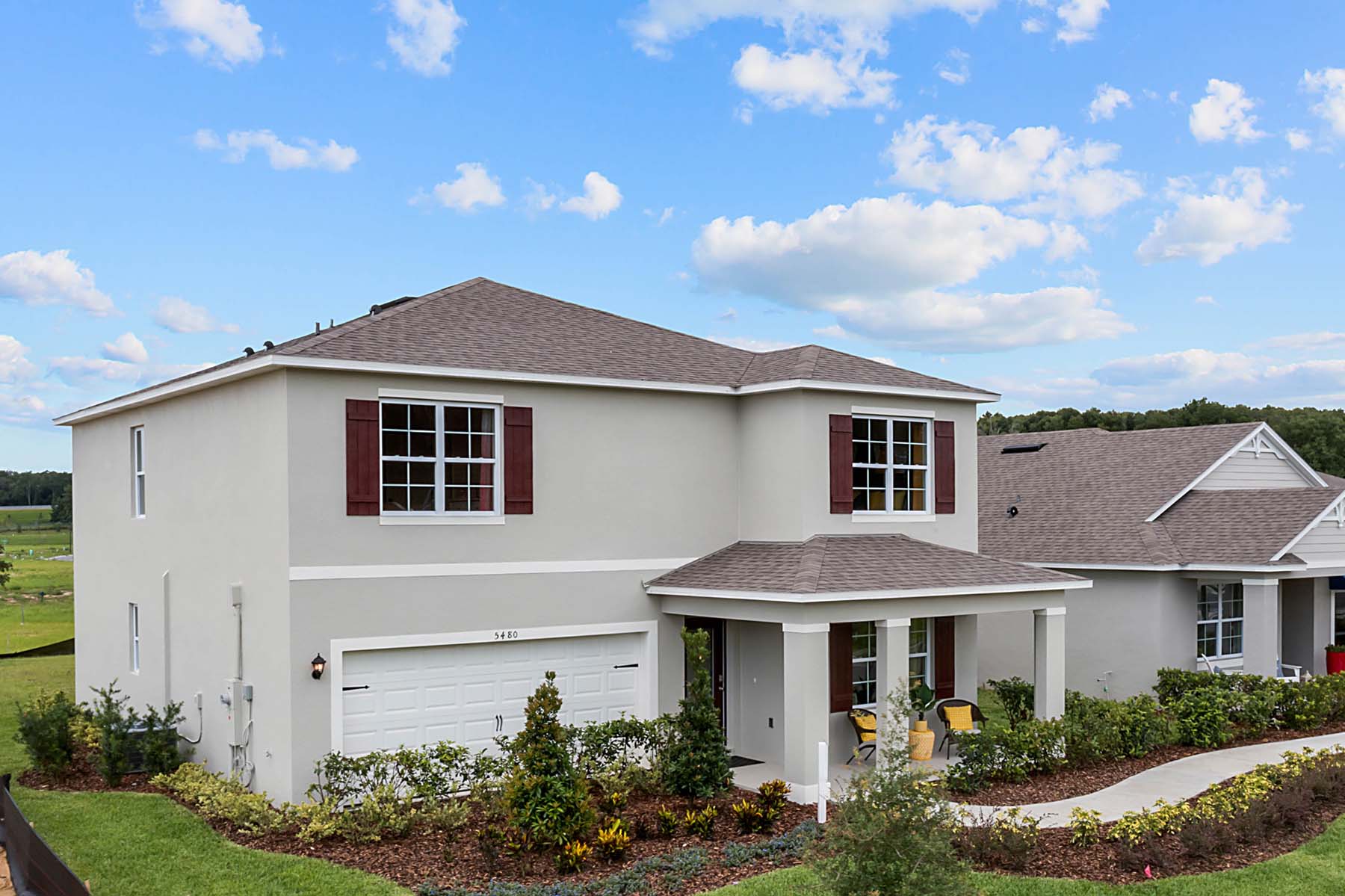 Two-story new home with siding, covered porch and 2 car garage.