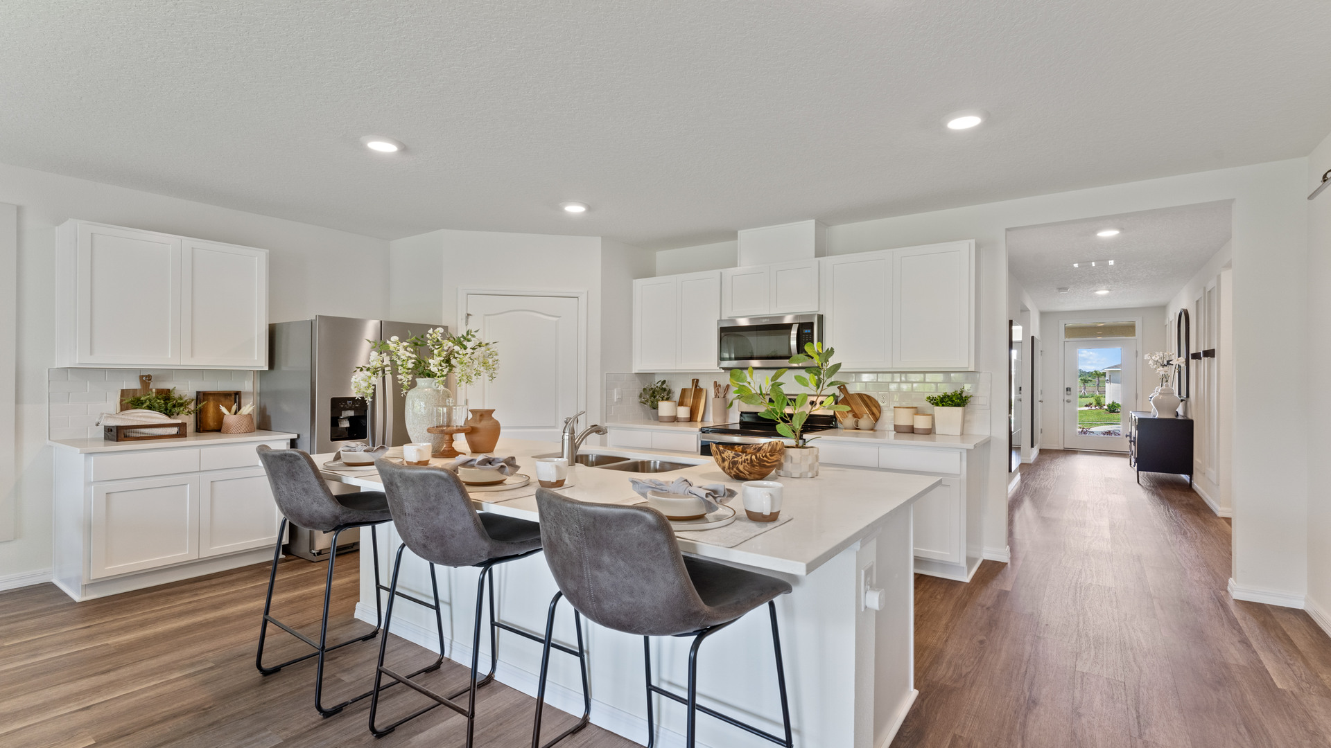 Kitchen with island seating, quartz counters, spacious pantry and stainless steel appliances.