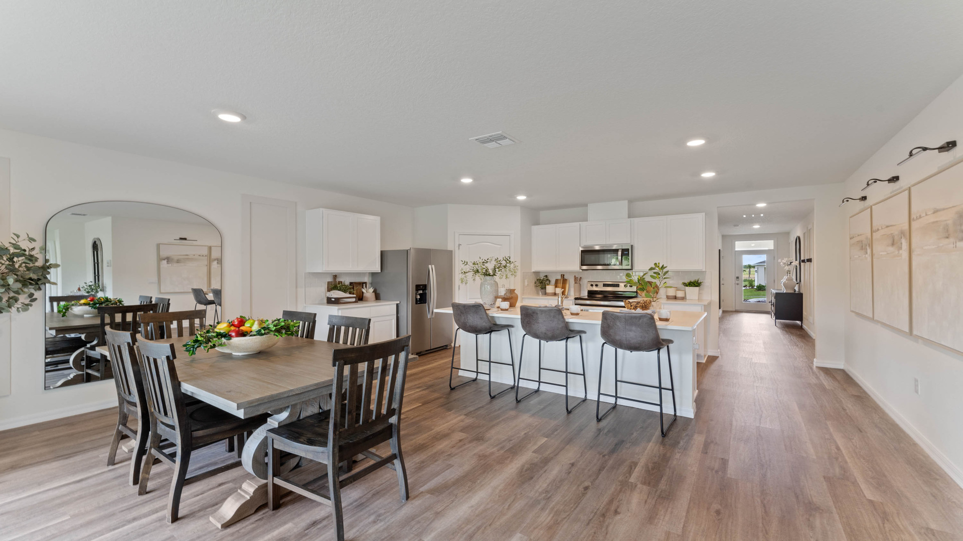 Spacious room showing dining room table with seating adjacent to kitchen, with island, seating.