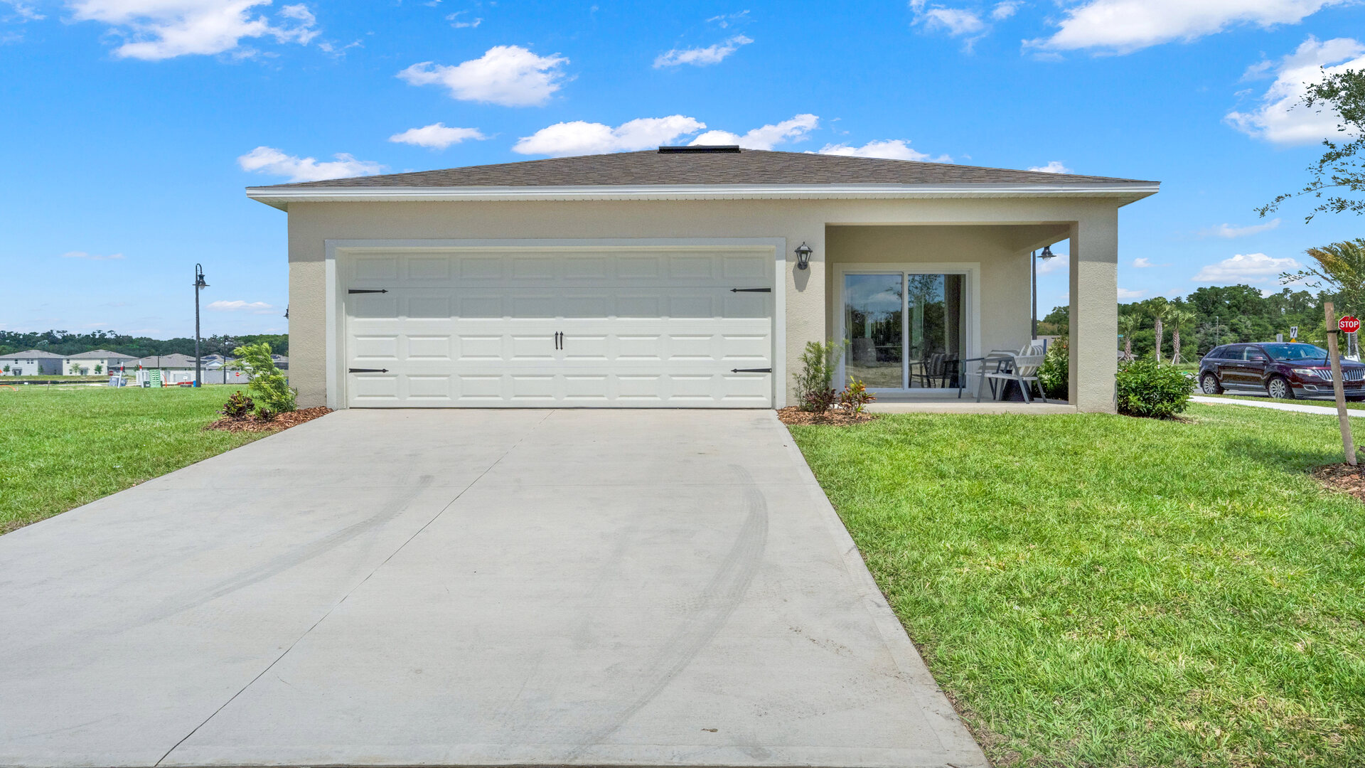 Rear of home with view of grassed backyard, porch seating and slider doors.