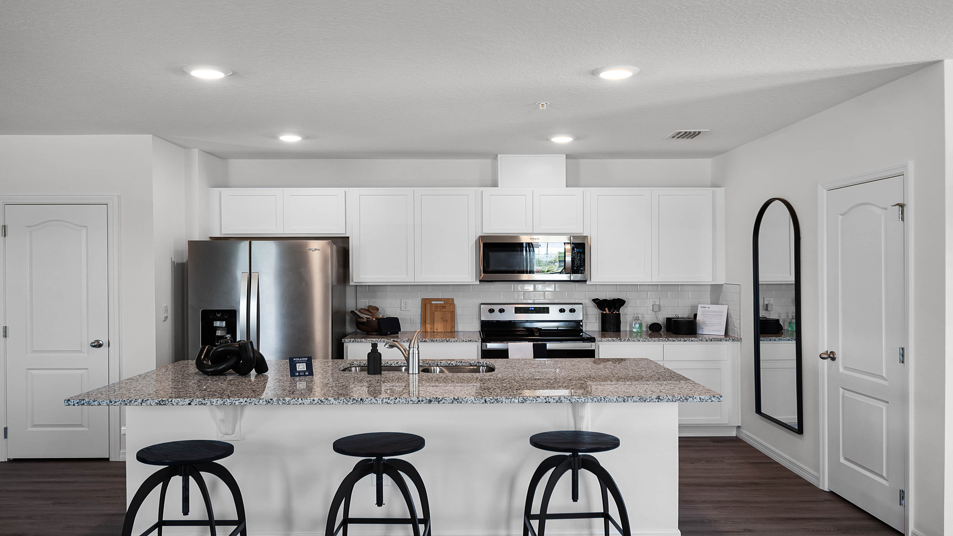 Kitchen with island seating, granite counters, spacous pantry and stainless steel appliances.