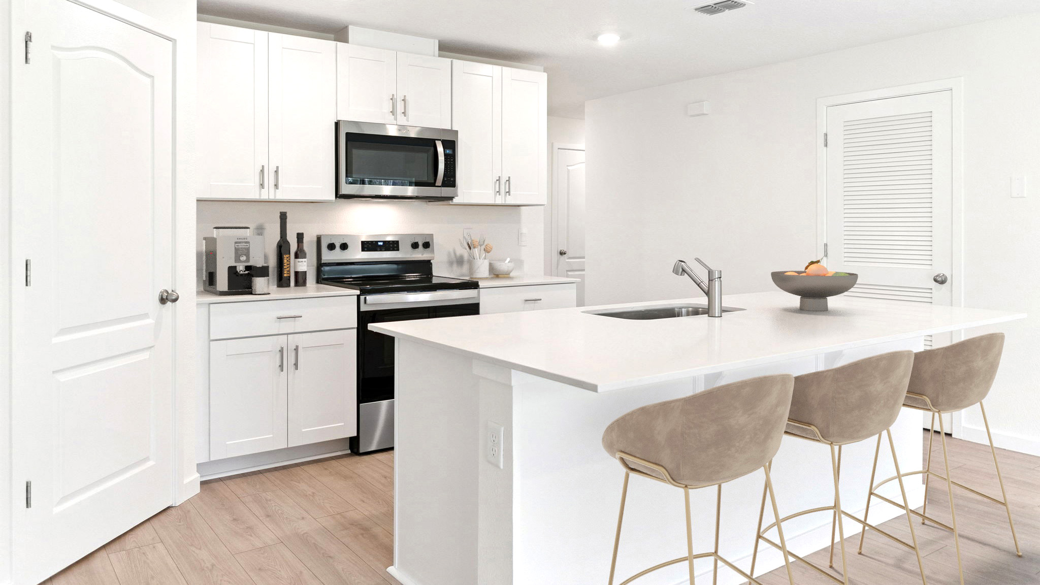 Kitchen with island seating, quartz counters, spacious pantry and stainless steel appliances.