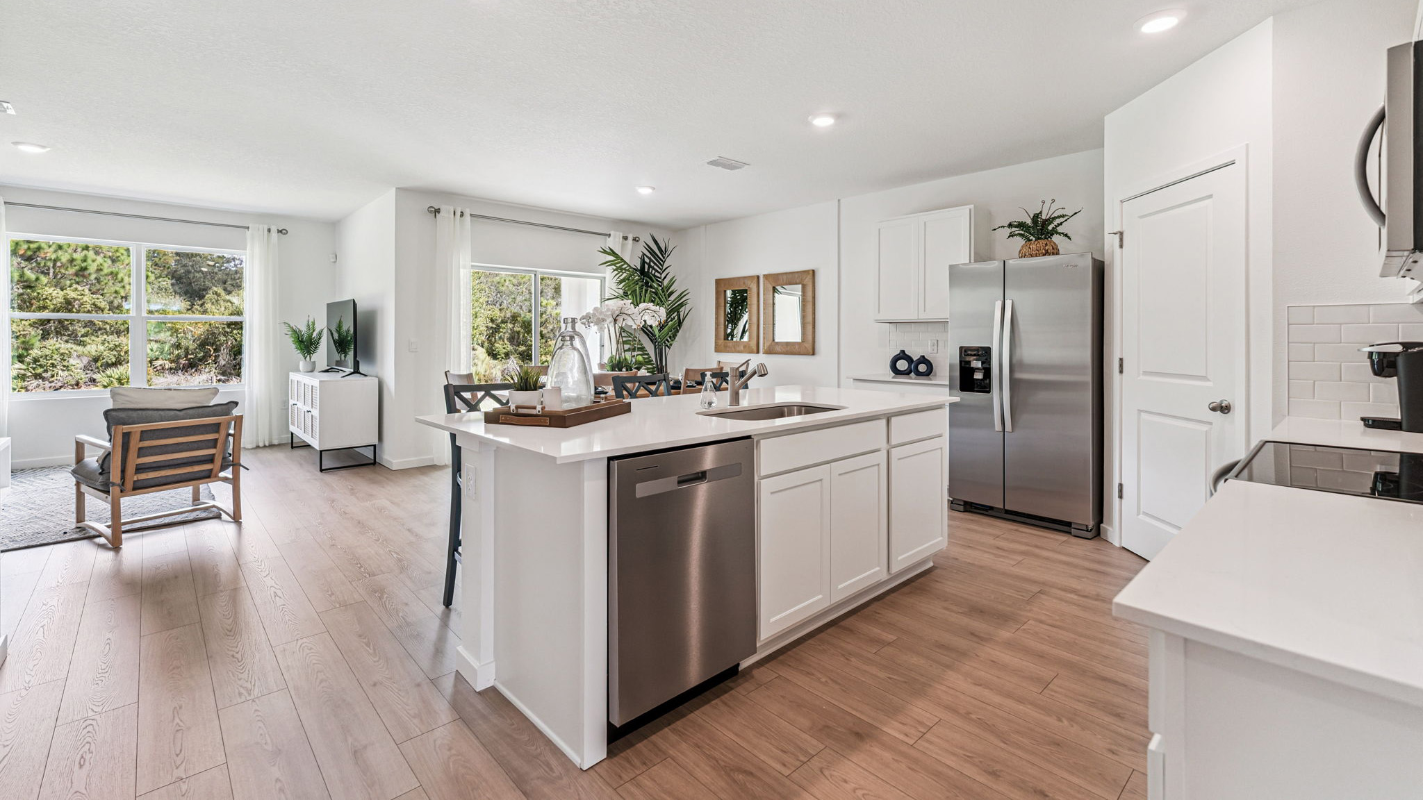 Kitchen with island seating, quartz counters, spacious pantry and stainless steel appliances.