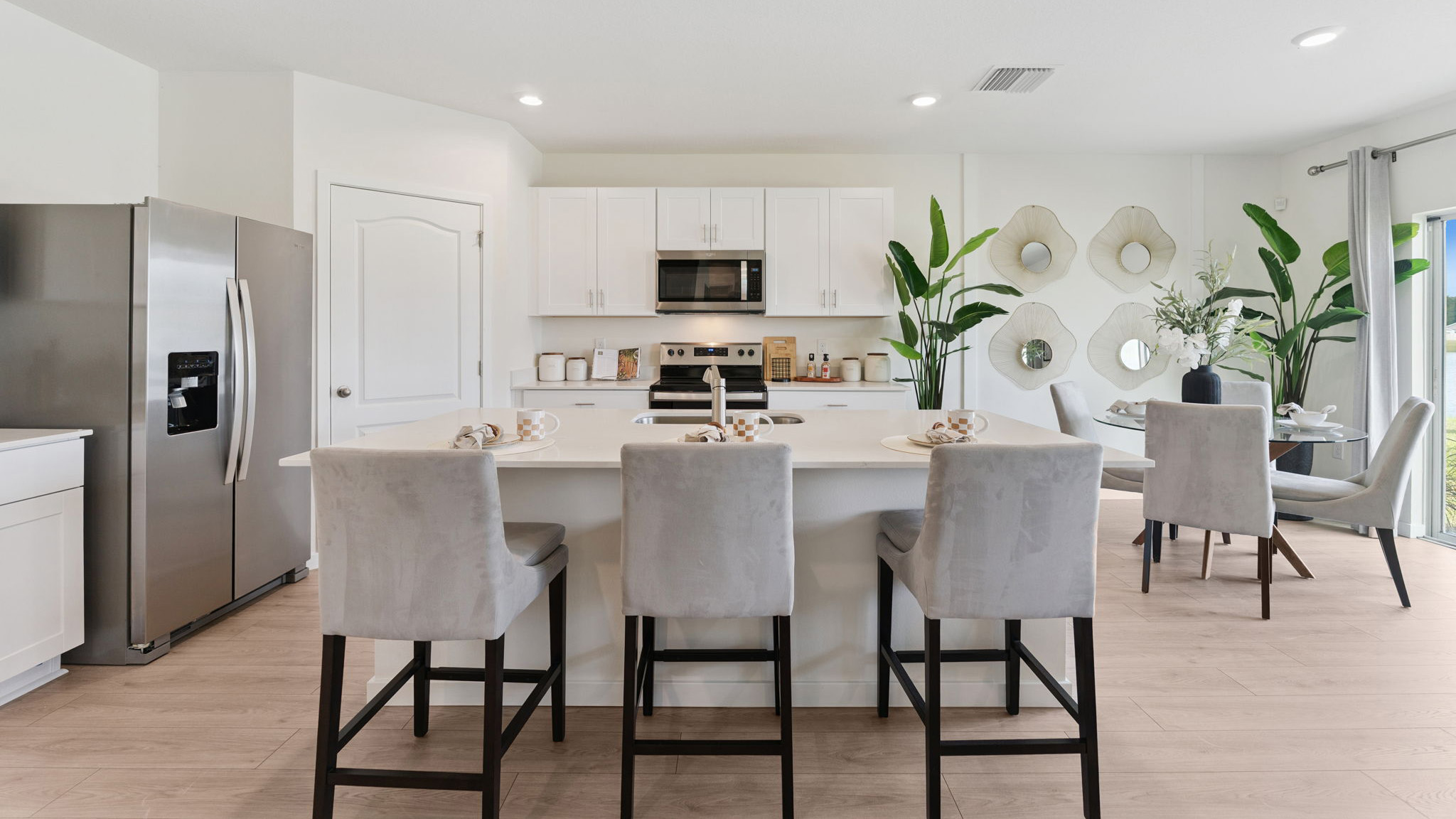 Kitchen with island seating, quartz counters, spacious pantry and stainless steel appliances.