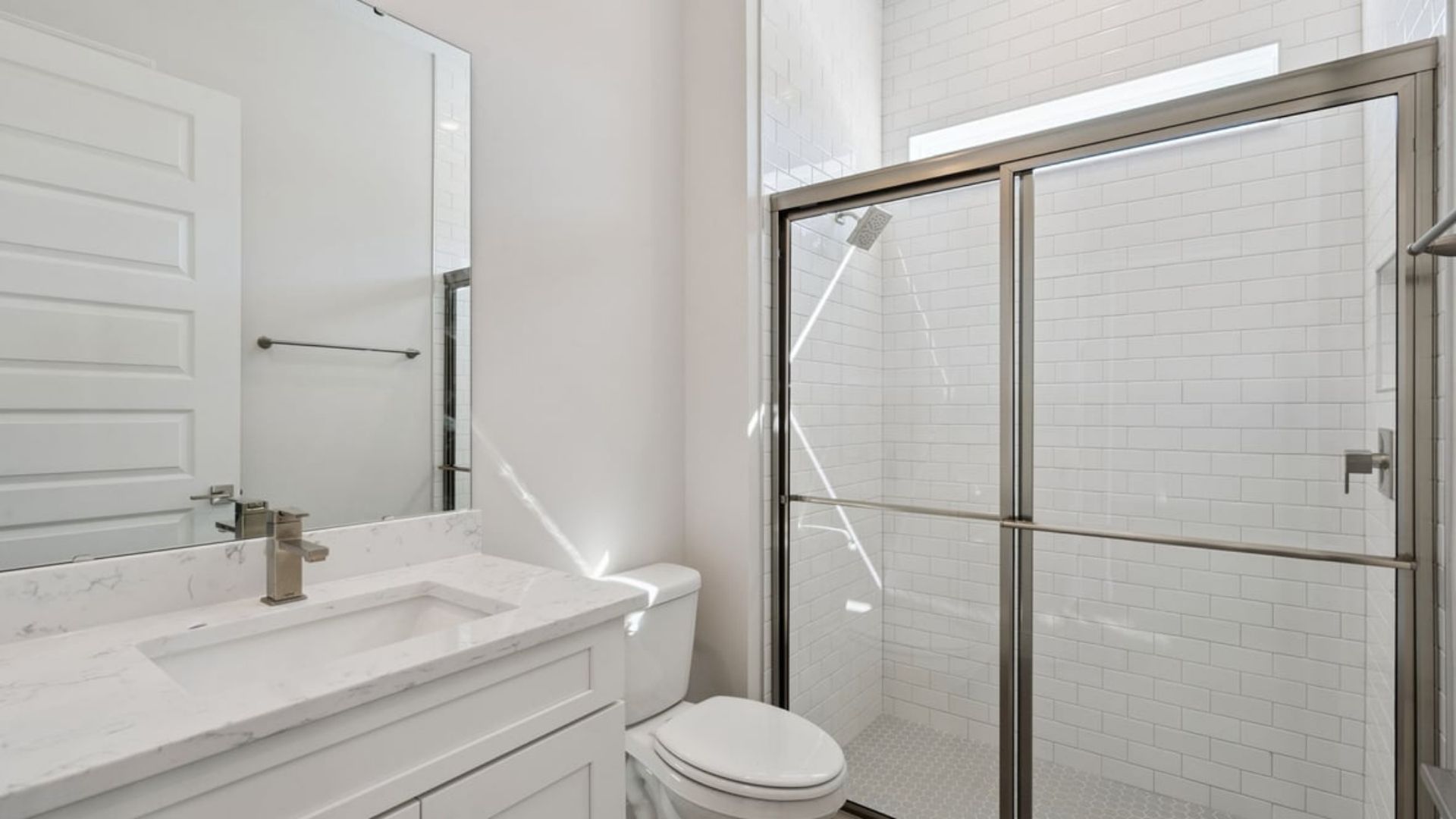Modern bathroom with single vanity, large wall mirror, cabinets and quartz countertops