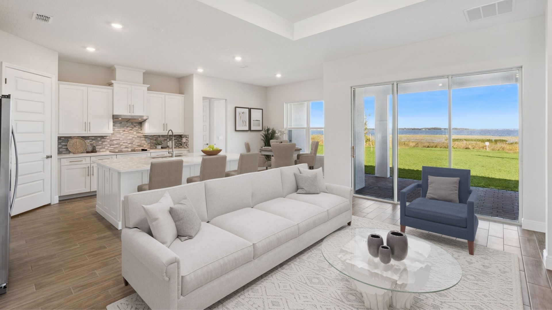 Living area with couch seating overseeing kitchen and dining room with laminate flooring and lake view