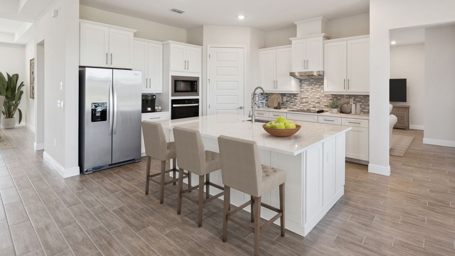 Kitchen with island seating, quartz counters, spacous pantry and stainless steel appliances.