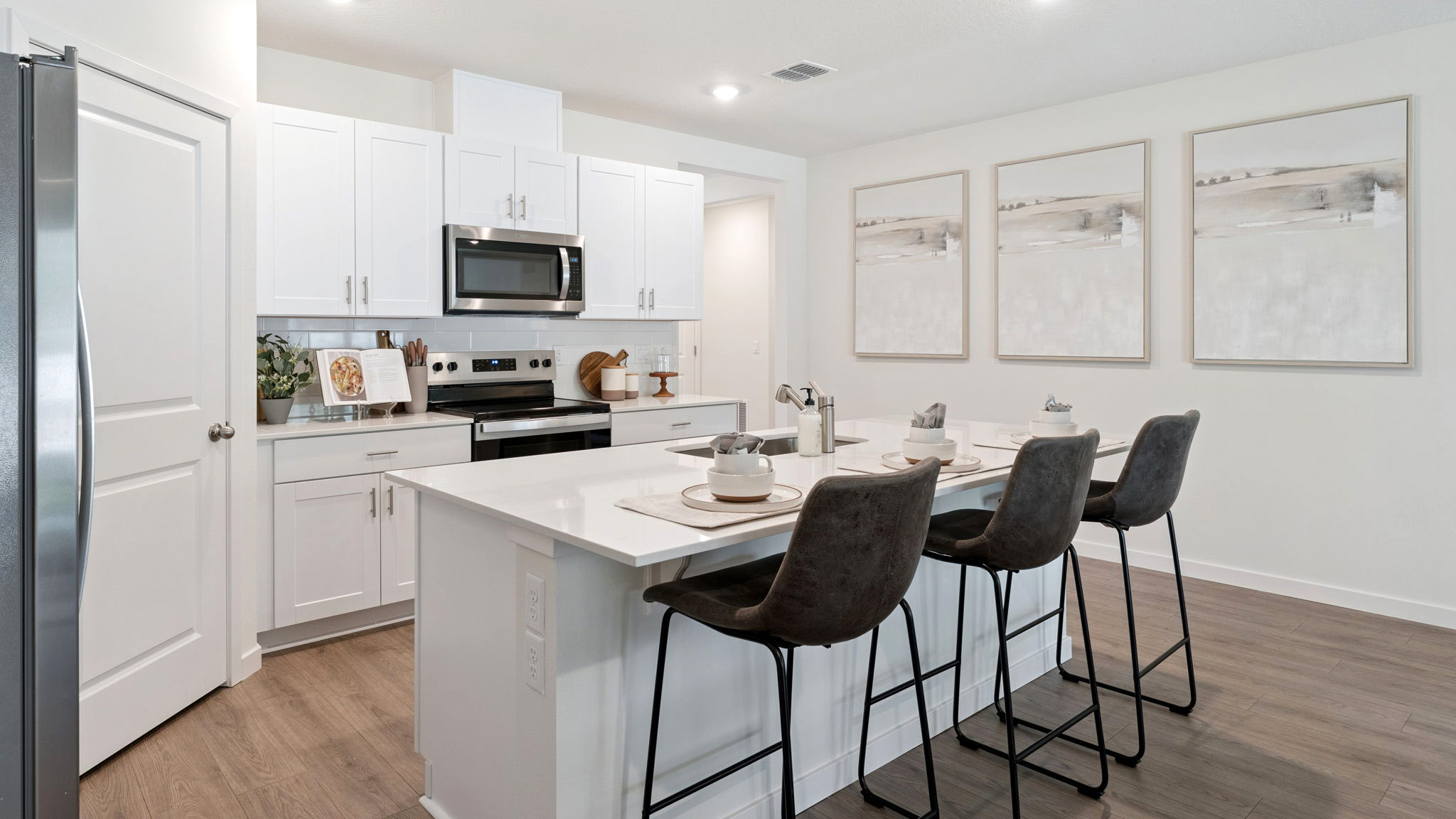 Kitchen with island seating, quartz counters, spacious pantry and stainless steel appliances.