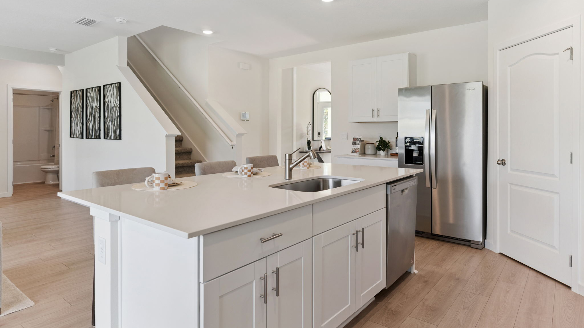 Kitchen with island seating, quartz counters, spacious pantry and stainless steel appliances.