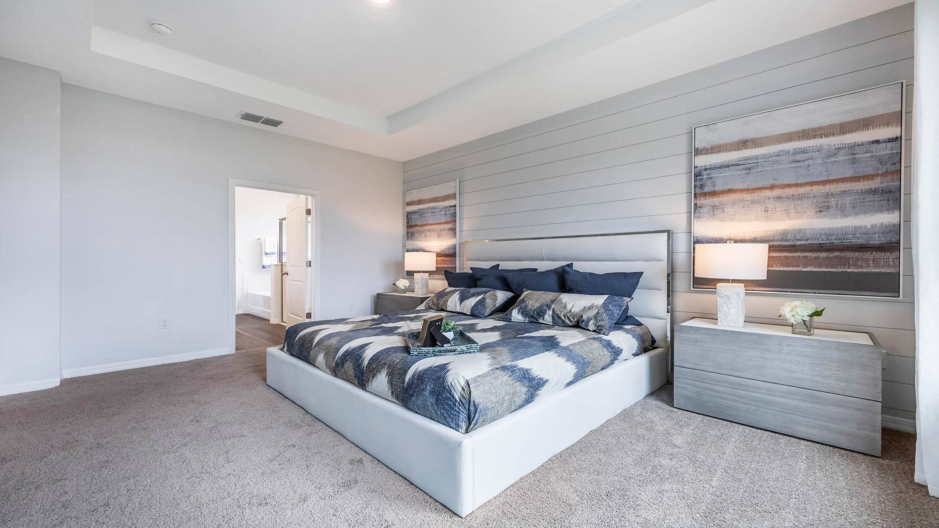 Spacious primary bedroom with king size bed, carpet flooring, natural lighting.