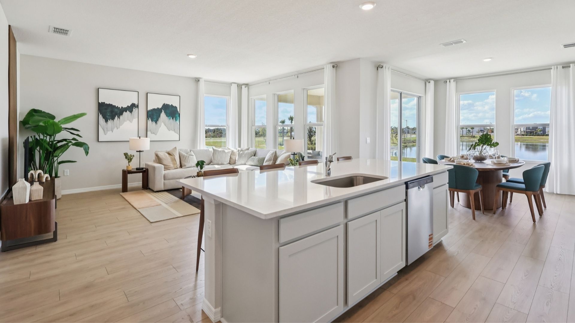 Kitchen with island seating, quartz counters, spacious pantry and stainless steel appliances showing entry way to home overseeing living area.