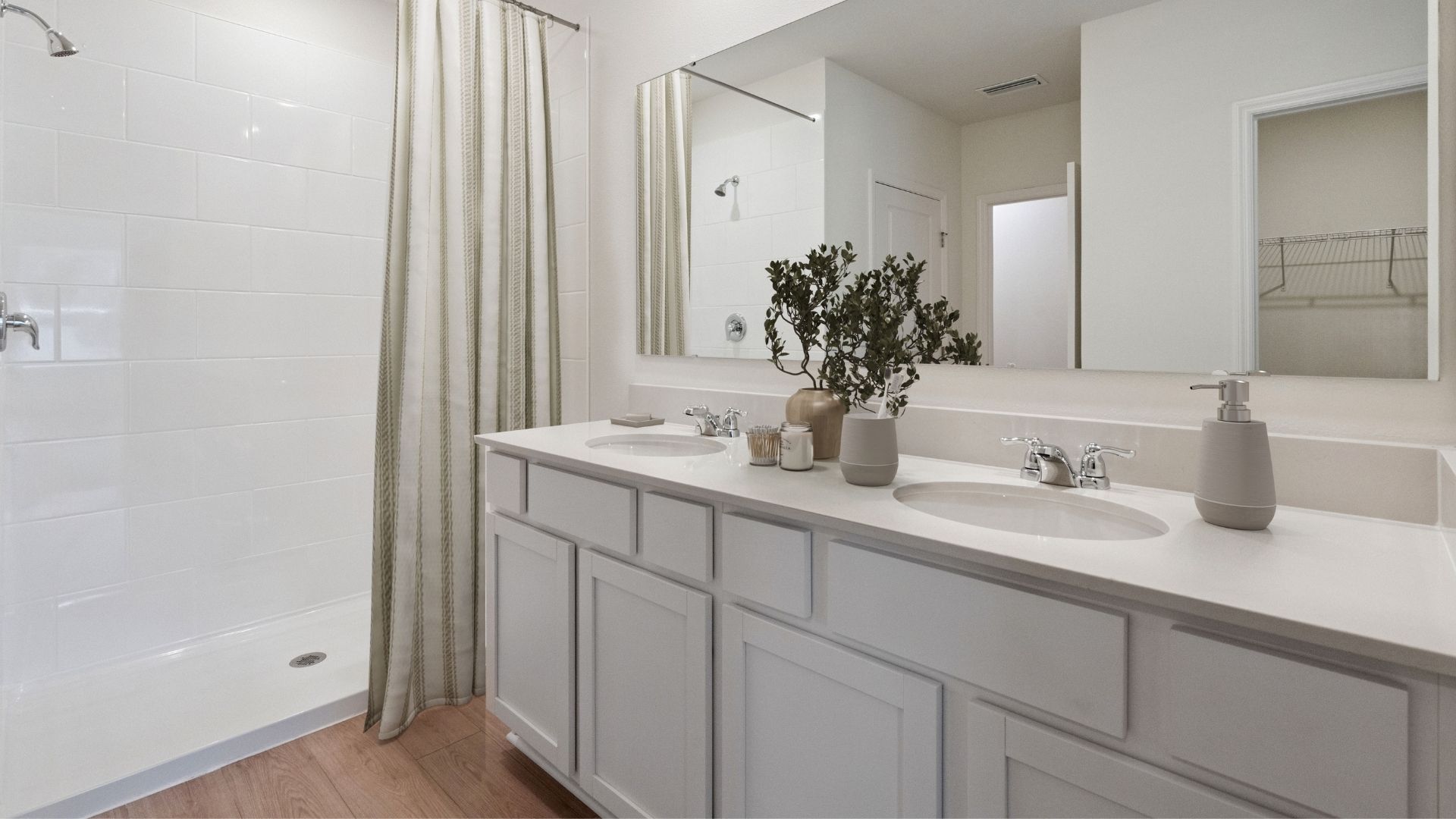 Modern bathroom with double vanity, large wall mirror, cabinets and quartz countertops along with toilet and walk-in shower