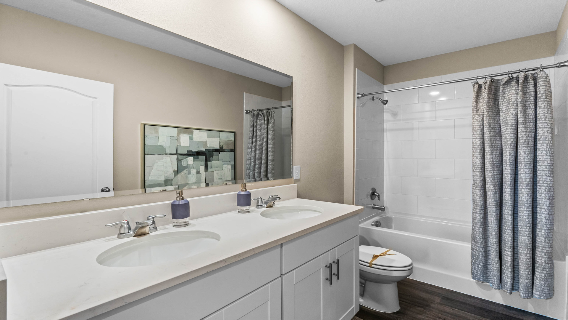 Modern bathroom with double vanity, large wall mirror, cabinets and quartz countertops