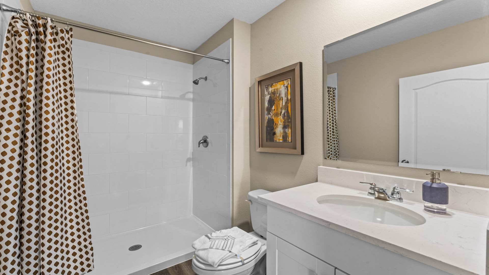 Modern bathroom with single vanity, large wall mirror, cabinets and quartz countertops