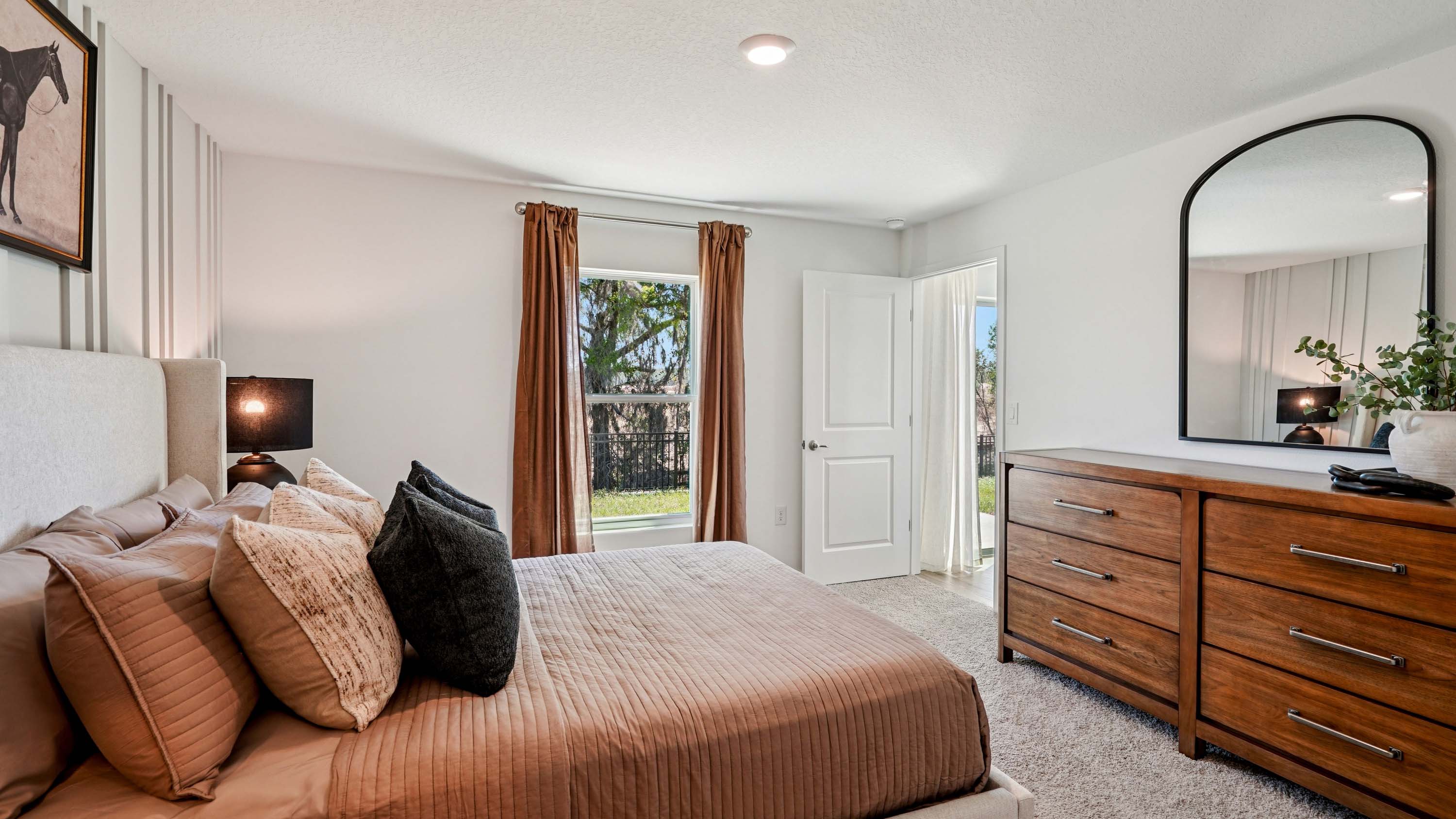 Spacious primary bedroom with bed, carpet flooring, natural lighting showing access to primary bathroom.