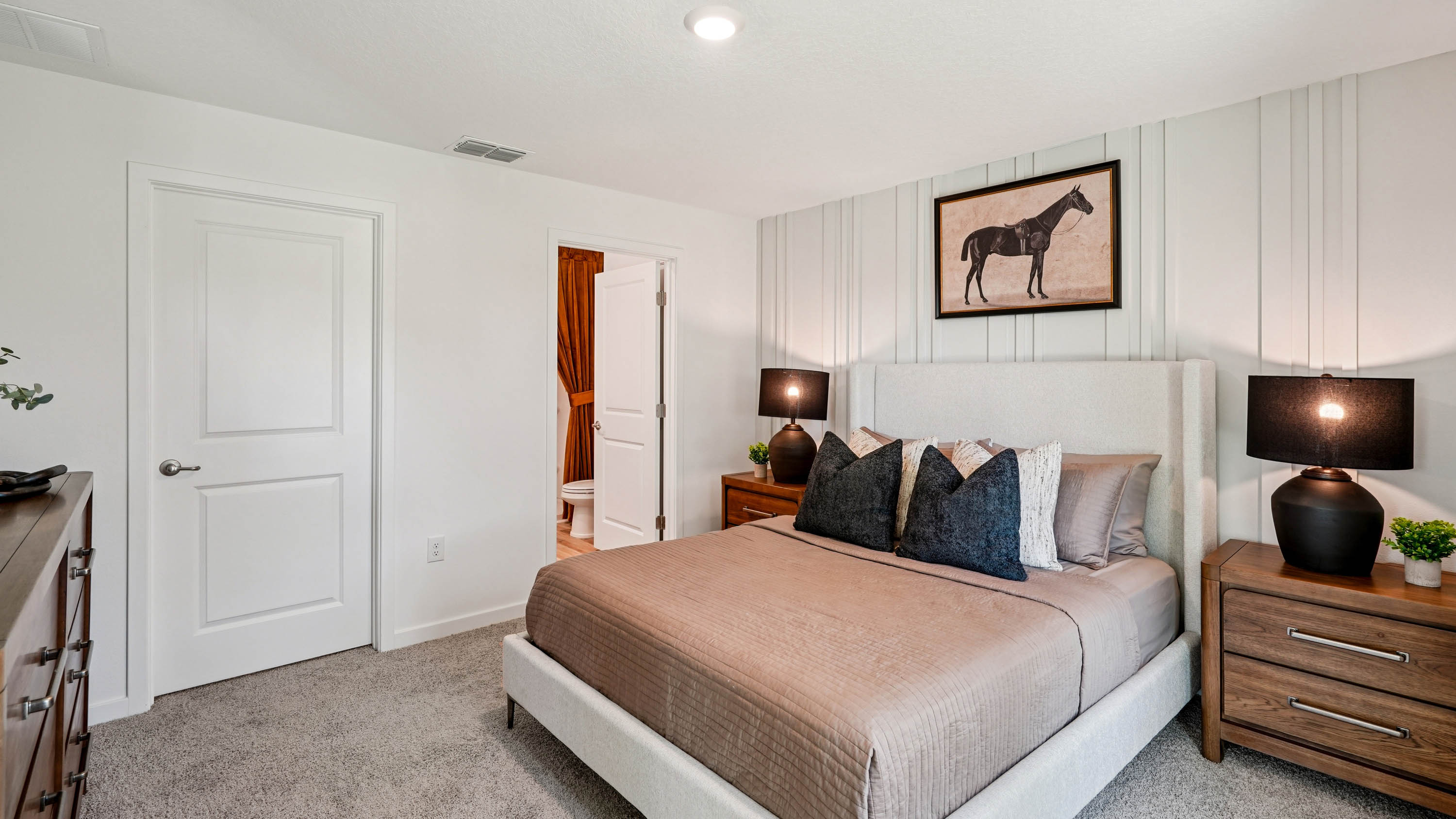 Spacious primary bedroom with bed, carpet flooring, natural lighting showing access to primary bathroom.