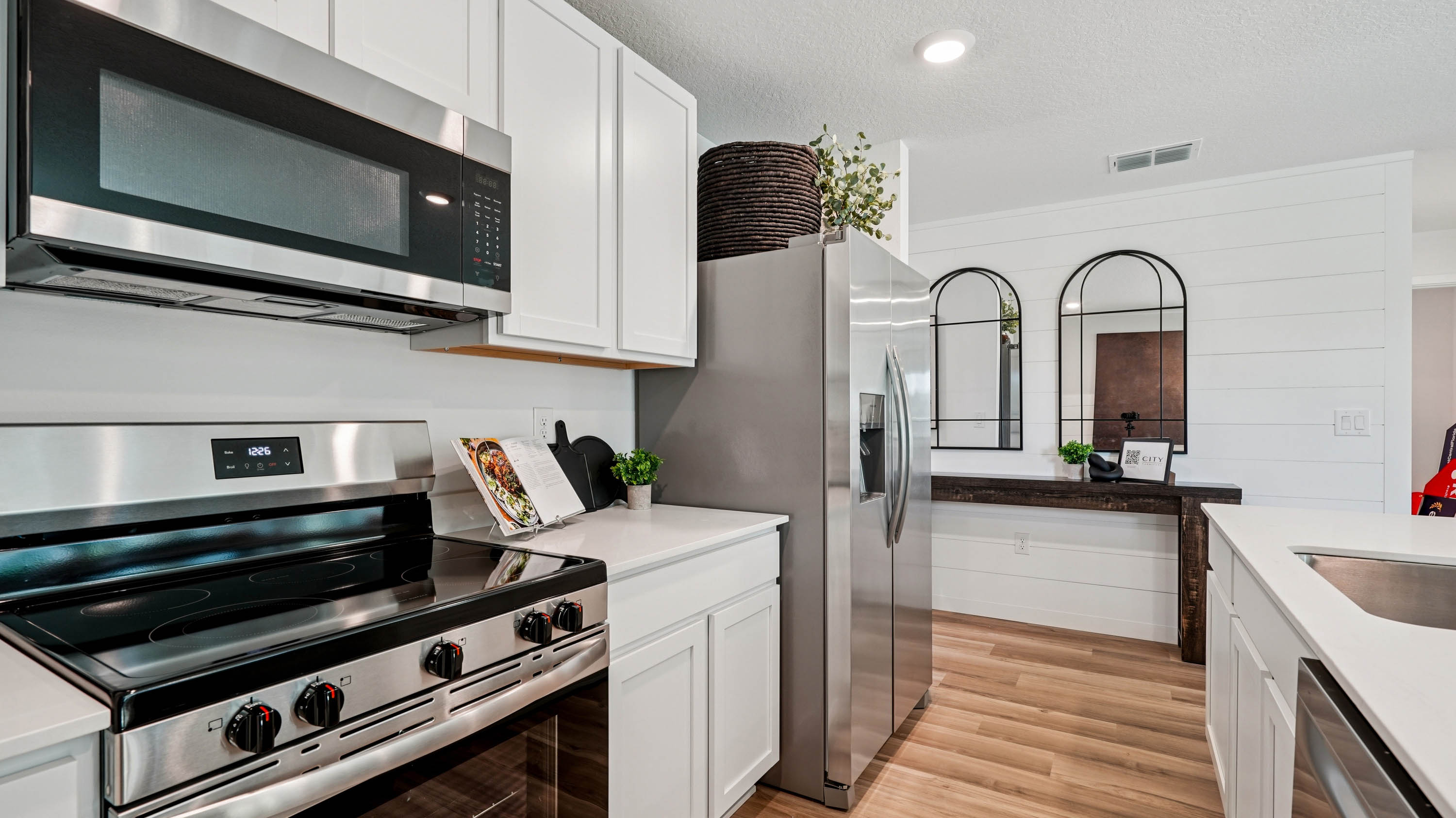 Kitchen with seating, quartz counters, spacious pantry and stainless steel appliances.