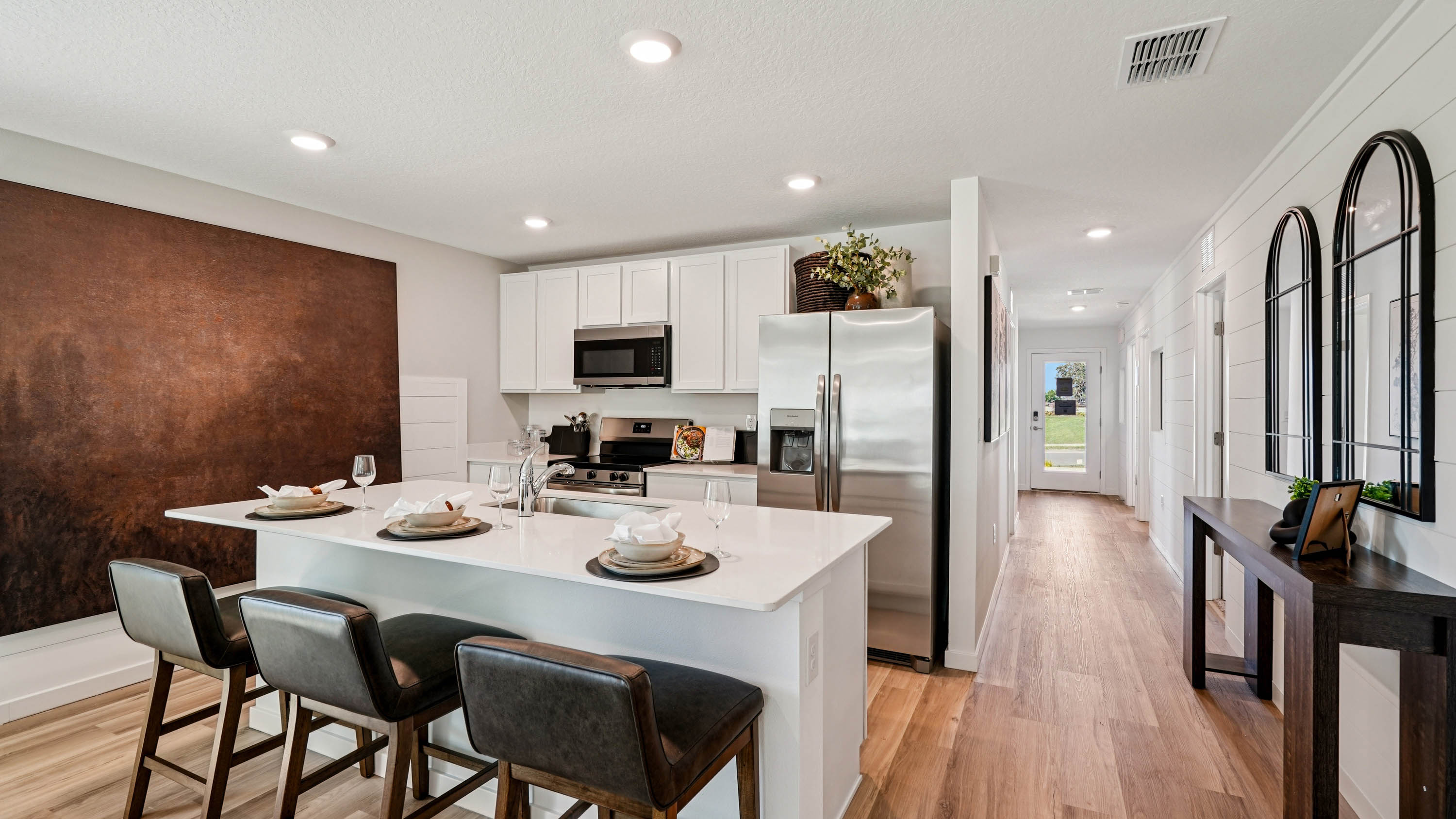 Kitchen with seating, quartz counters, spacious pantry and stainless steel appliances.