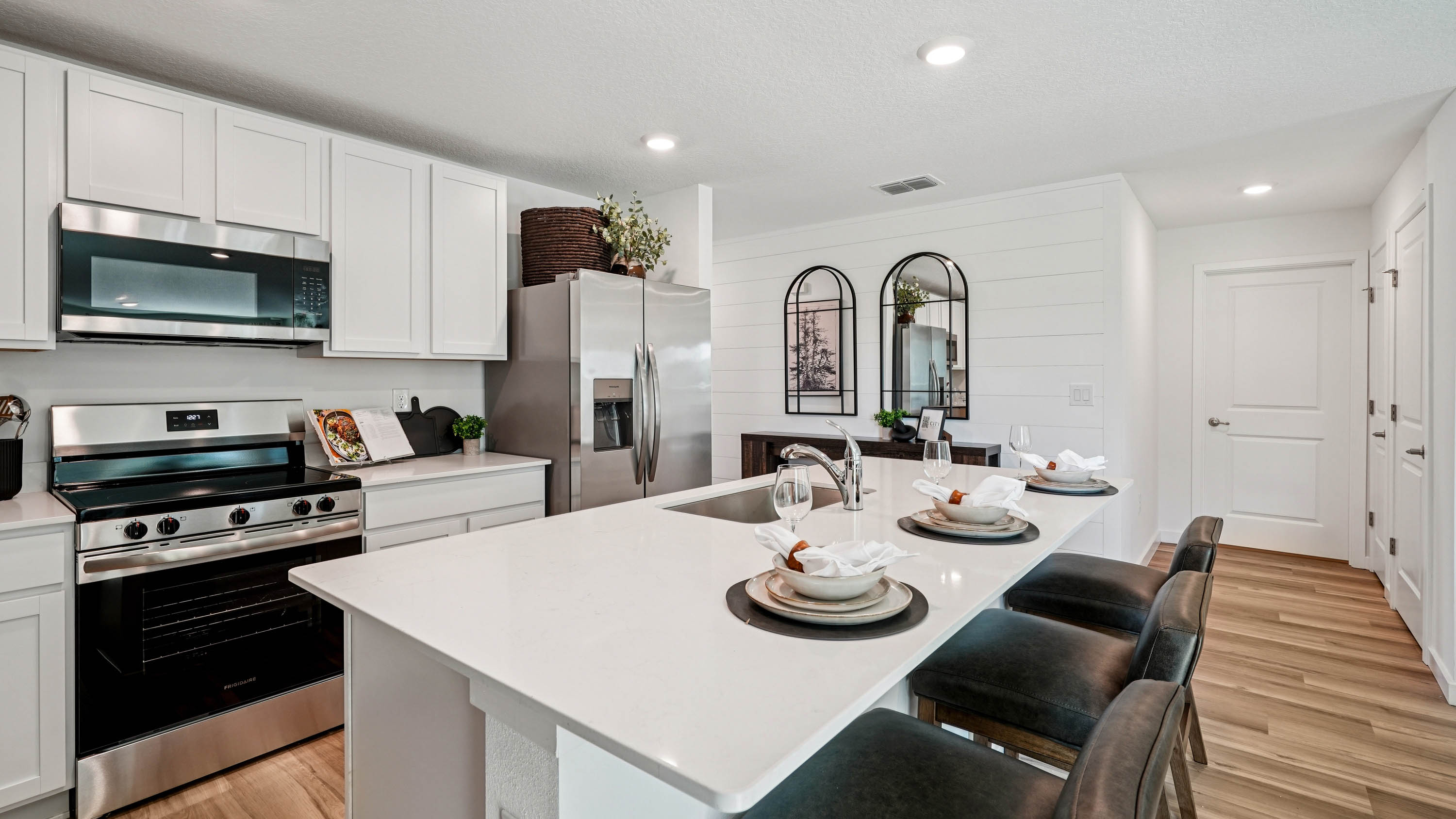 Kitchen with seating, quartz counters, spacious pantry and stainless steel appliances.