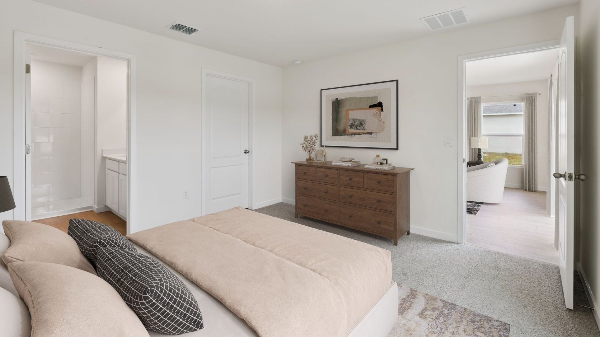 Spacious primary bedroom with bed, carpet flooring, natural lighting showing access to primary bathroom.