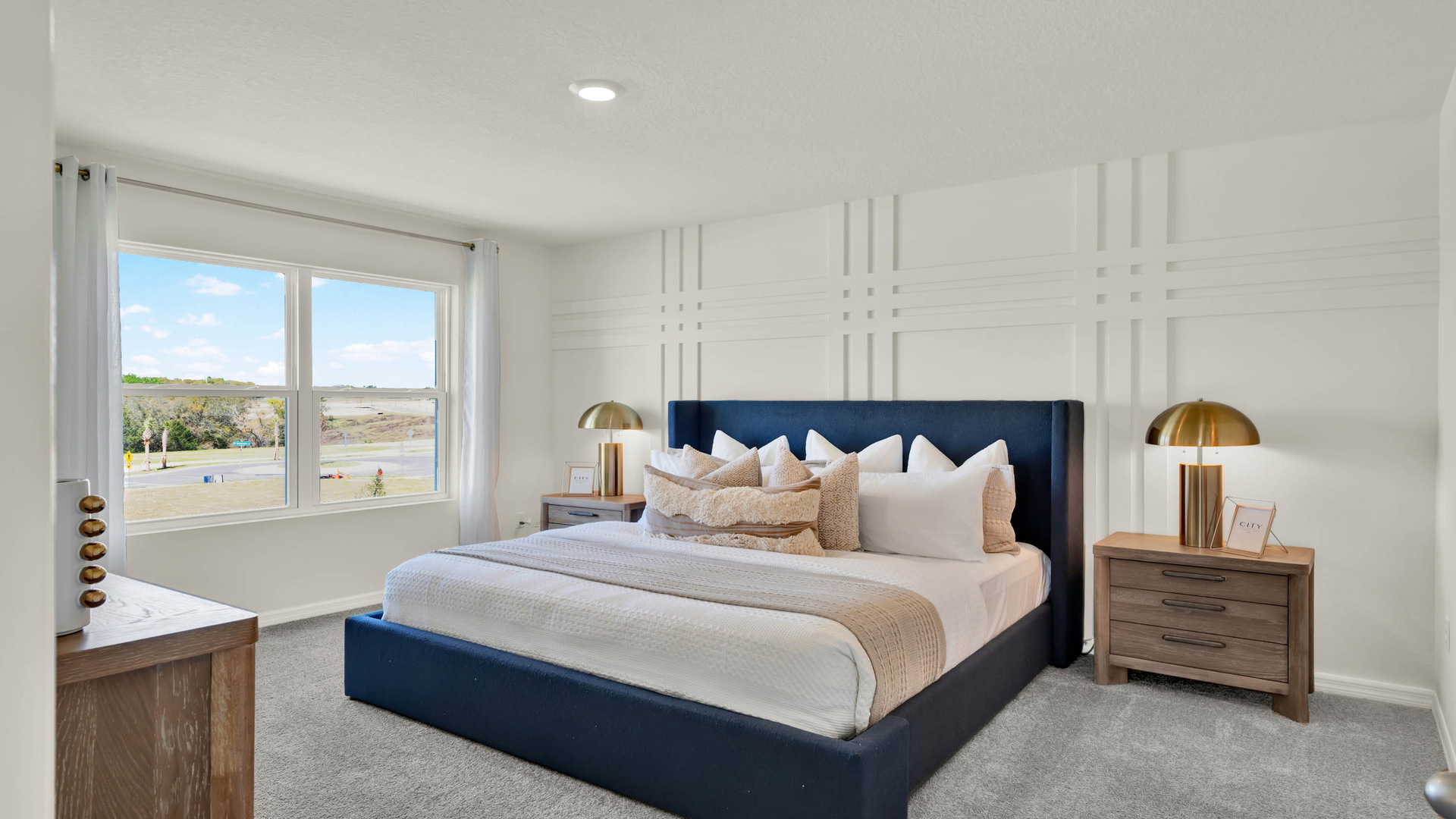 Spacious primary bedroom with king size bed, carpet flooring, natural lighting.