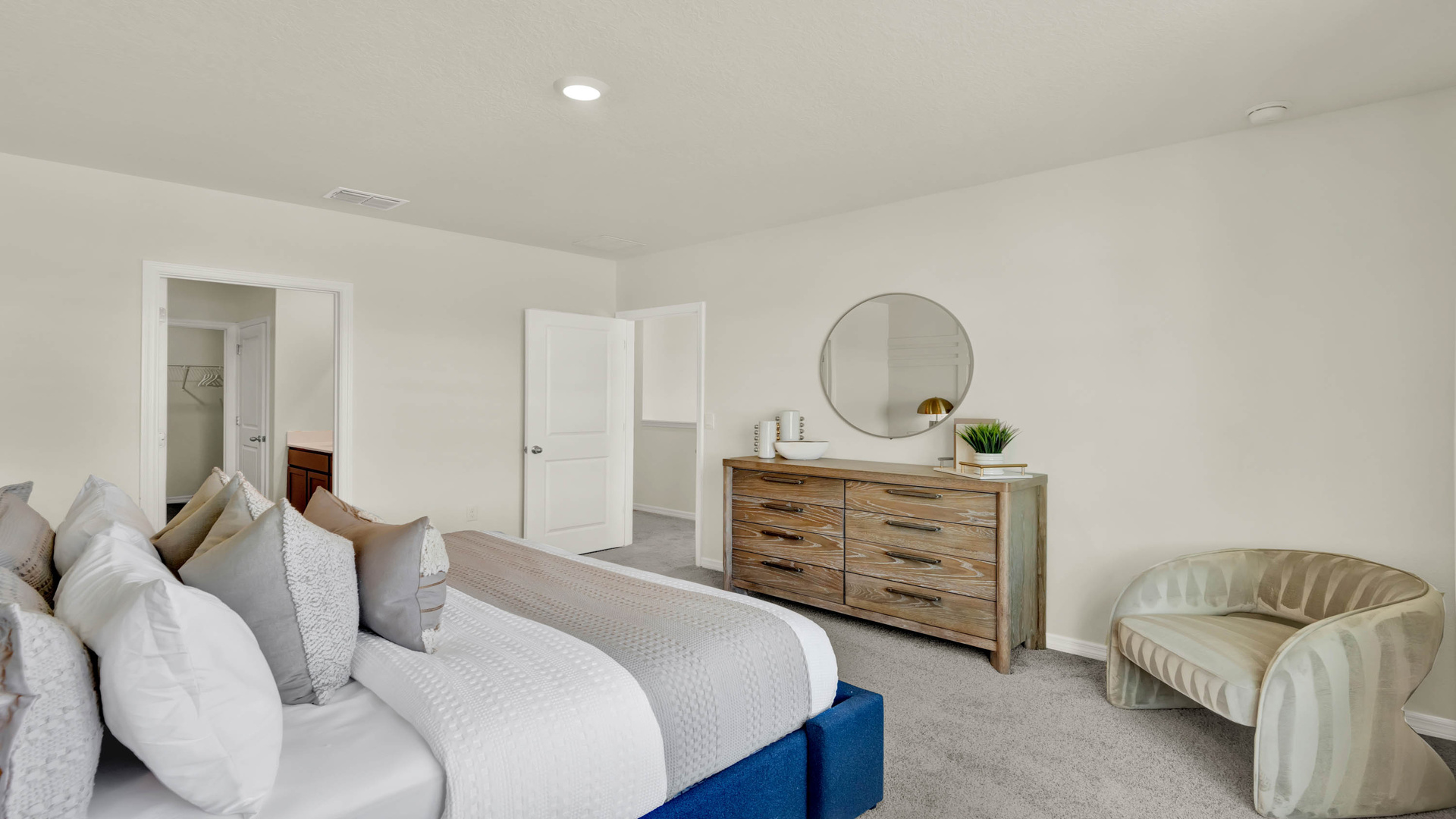 Spacious primary bedroom with king size bed, carpet flooring, natural lighting.