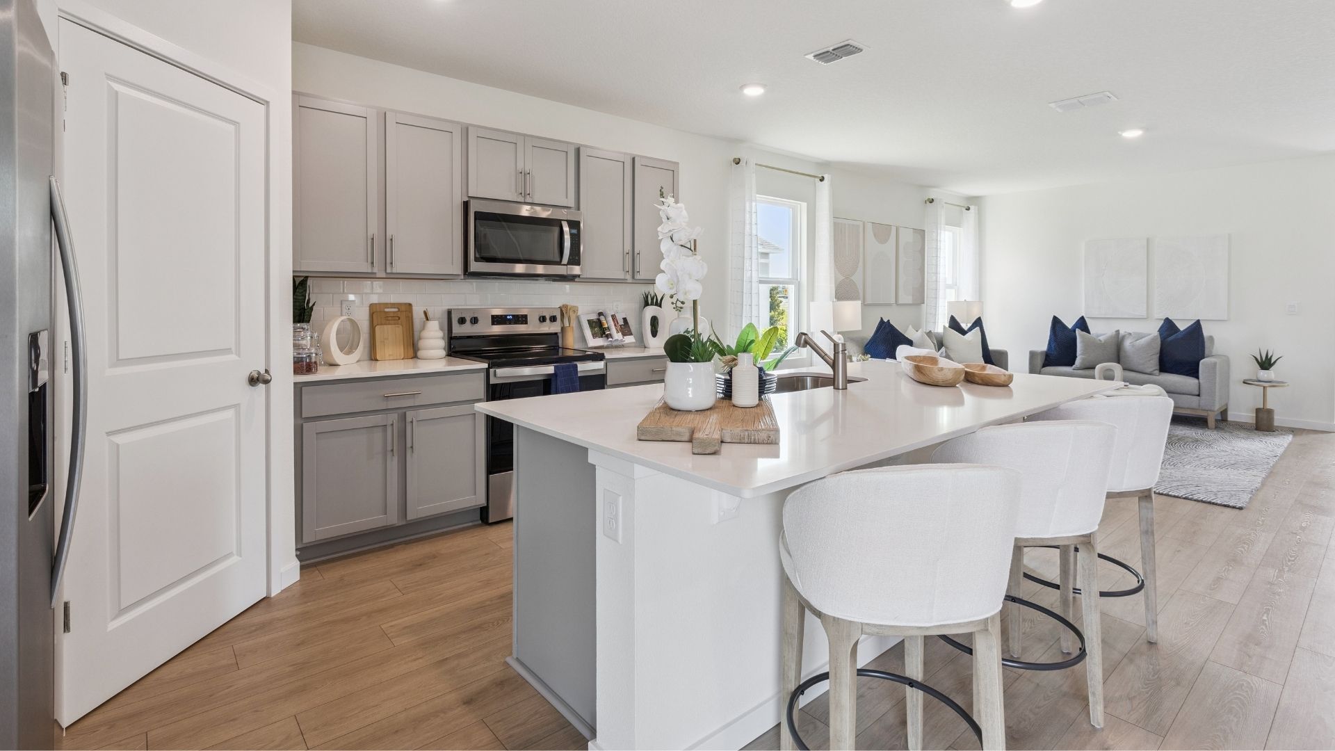 Kitchen with island seating, quartz counters, spacious pantry and stainless steel appliances.