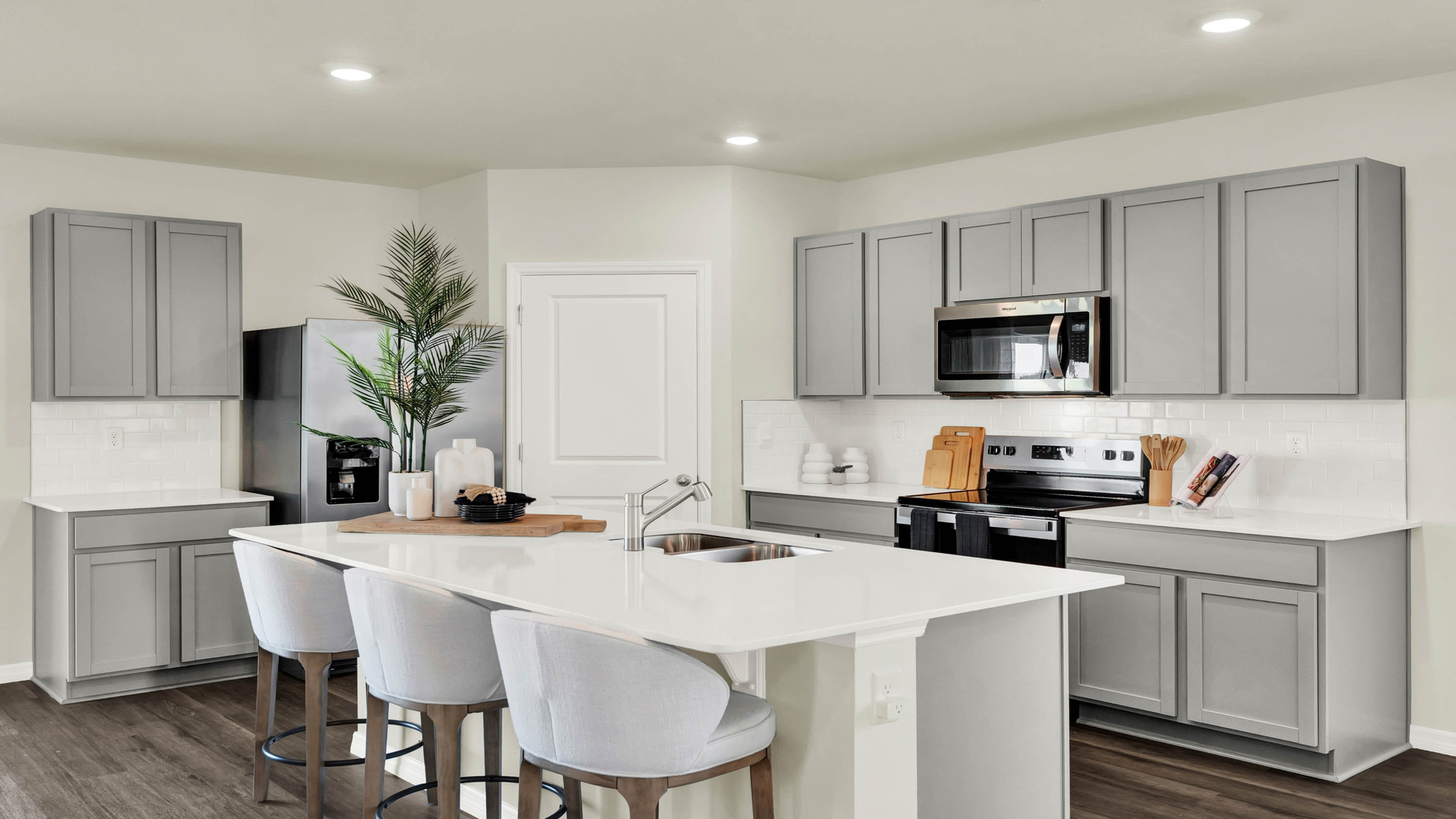 Kitchen with island seating, quartz counters, spacous pantry and stainless steel appliances.