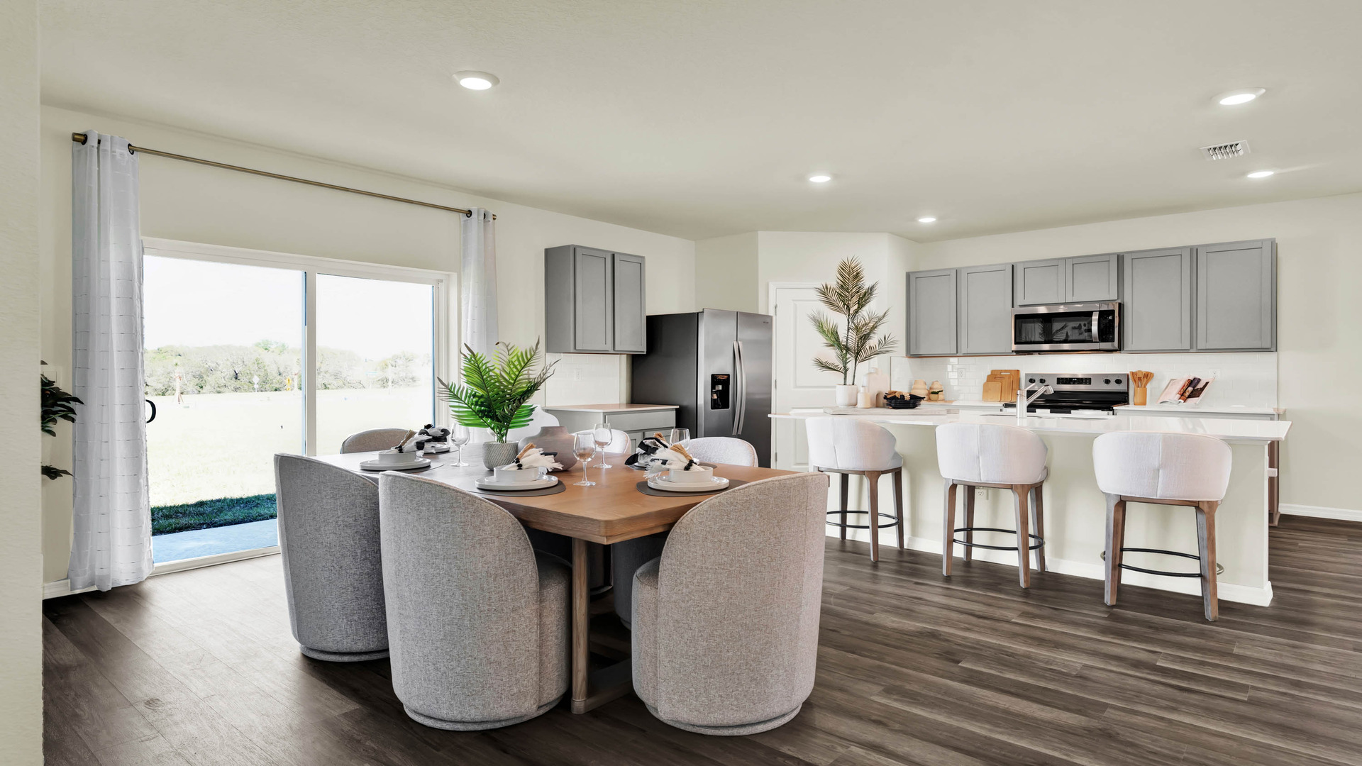 Dining room table by kitchen island with luxury vinyl plank flooring.