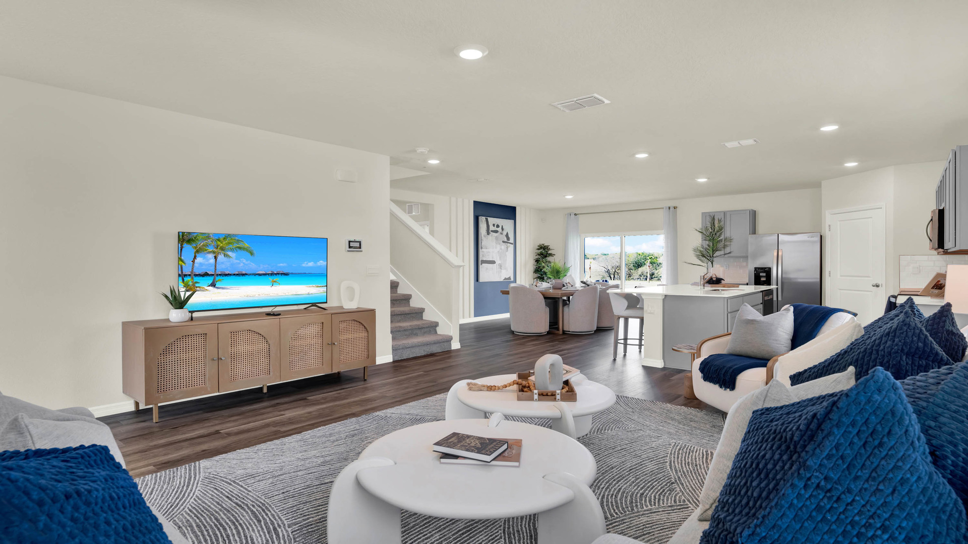 Living area with couch seating, natural lighting adjacent to kitchen and dinette.