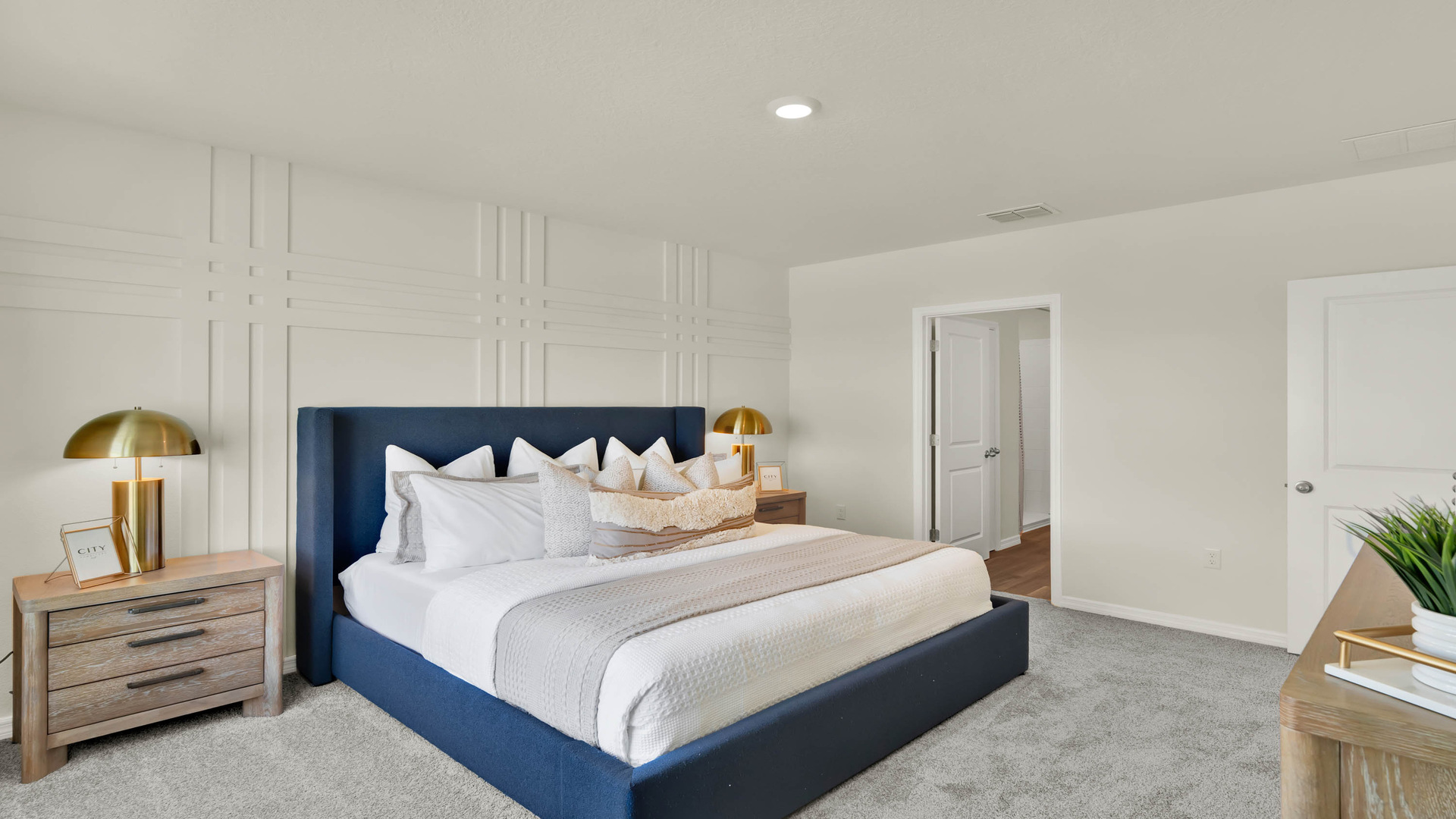 Spacious primary bedroom with king size bed, carpet flooring, natural lighting.