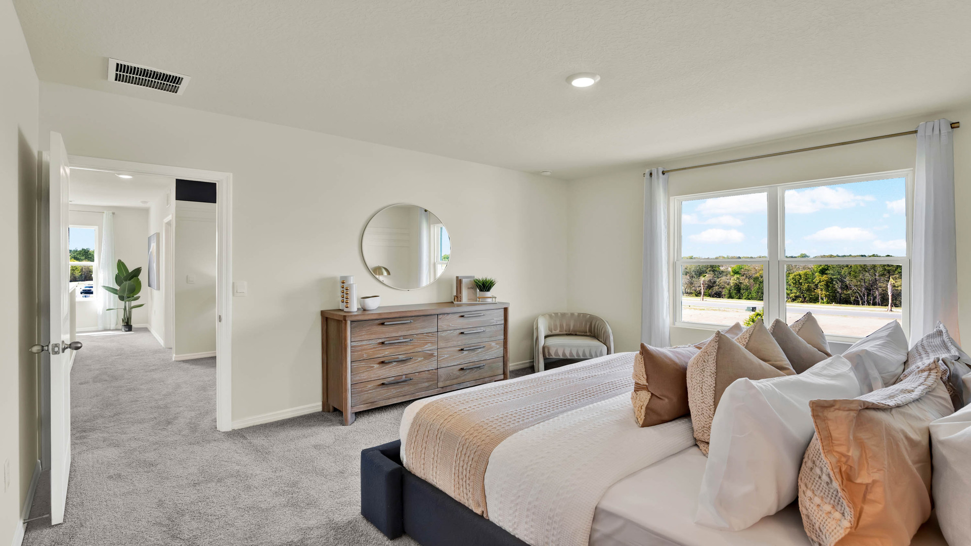 Spacious primary bedroom with king size bed, carpet flooring, natural lighting.