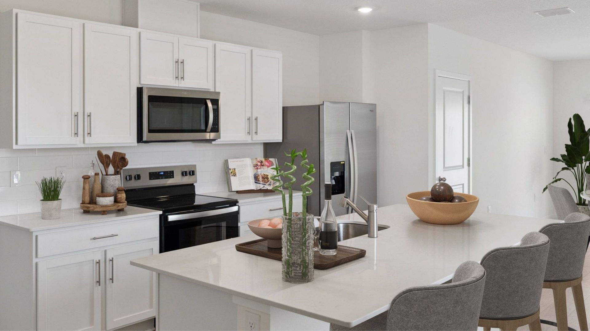 Kitchen with island seating, quartz counters, spacious pantry and stainless steel appliances.