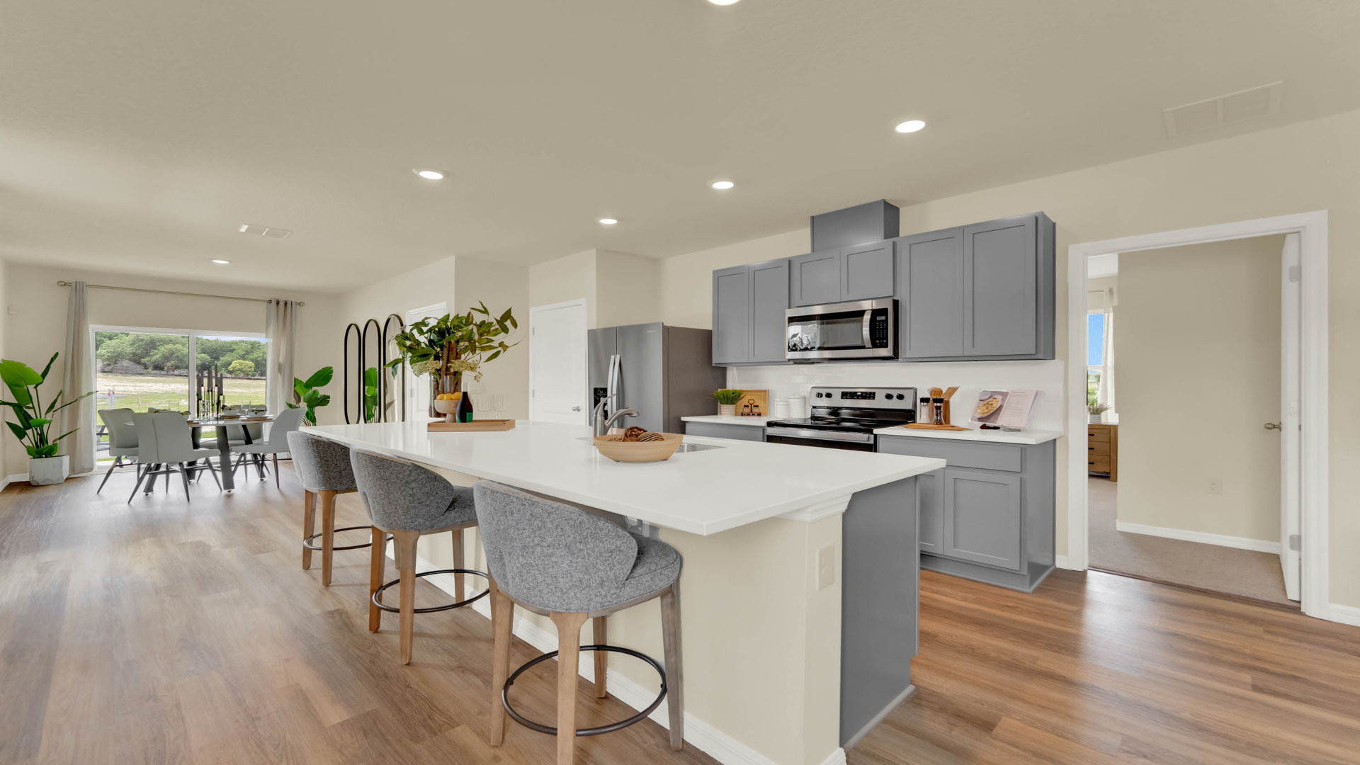Kitchen with island seating, quartz counters, spacous pantry and stainless steel appliances.