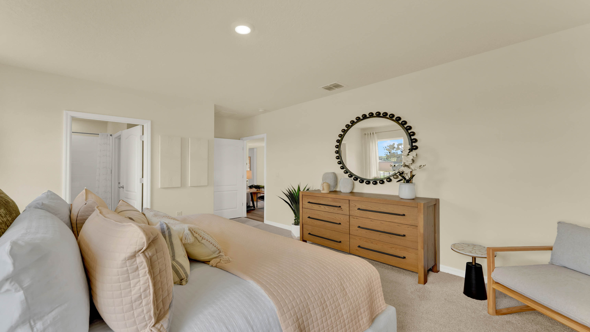 Spacious primary bedroom with king size bed, carpet flooring, natural lighting.