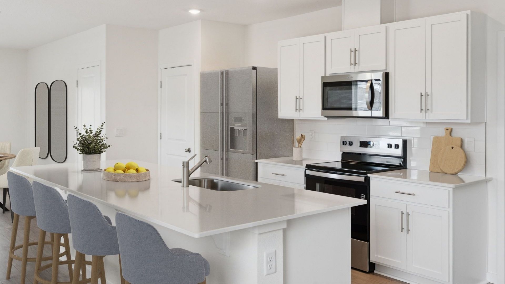 Kitchen with island seating, quartz counters, spacous pantry and stainless steel appliances.