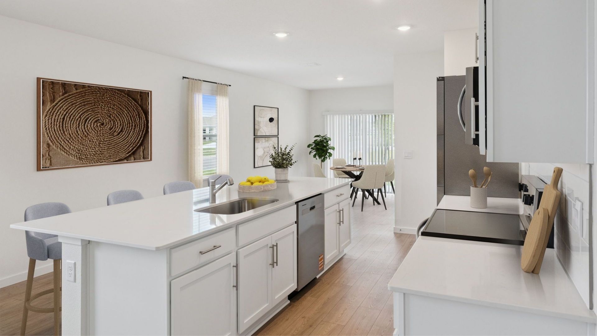 Kitchen with island seating, quartz counters, spacous pantry and stainless steel appliances overseeing dining room table