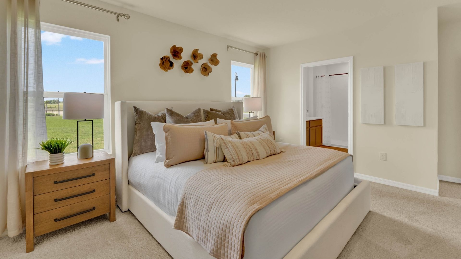 Spacious primary bedroom with king size bed, carpet flooring, natural lighting showing access to master bathroom.