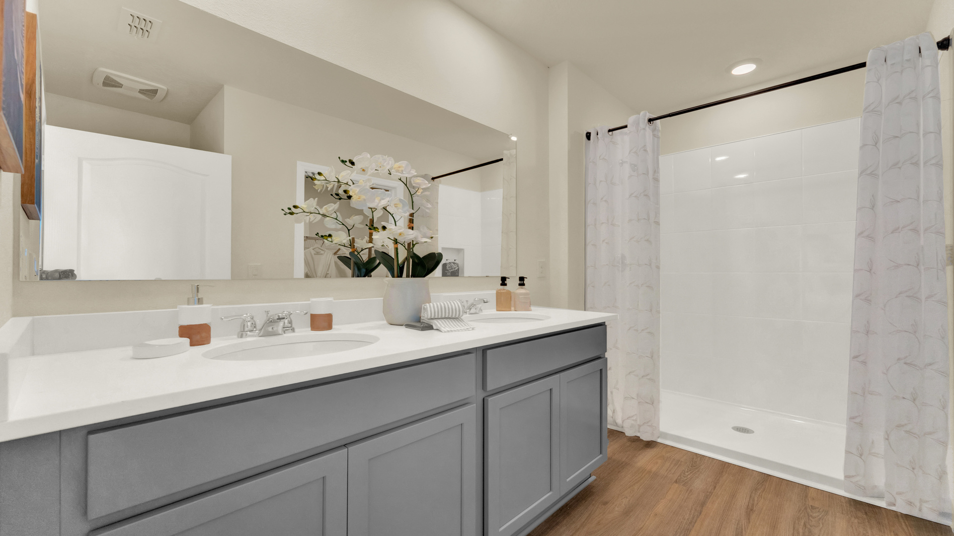 Modern bathroom with double vanity sinks, large wall mirror, cabinets and granite countertops.