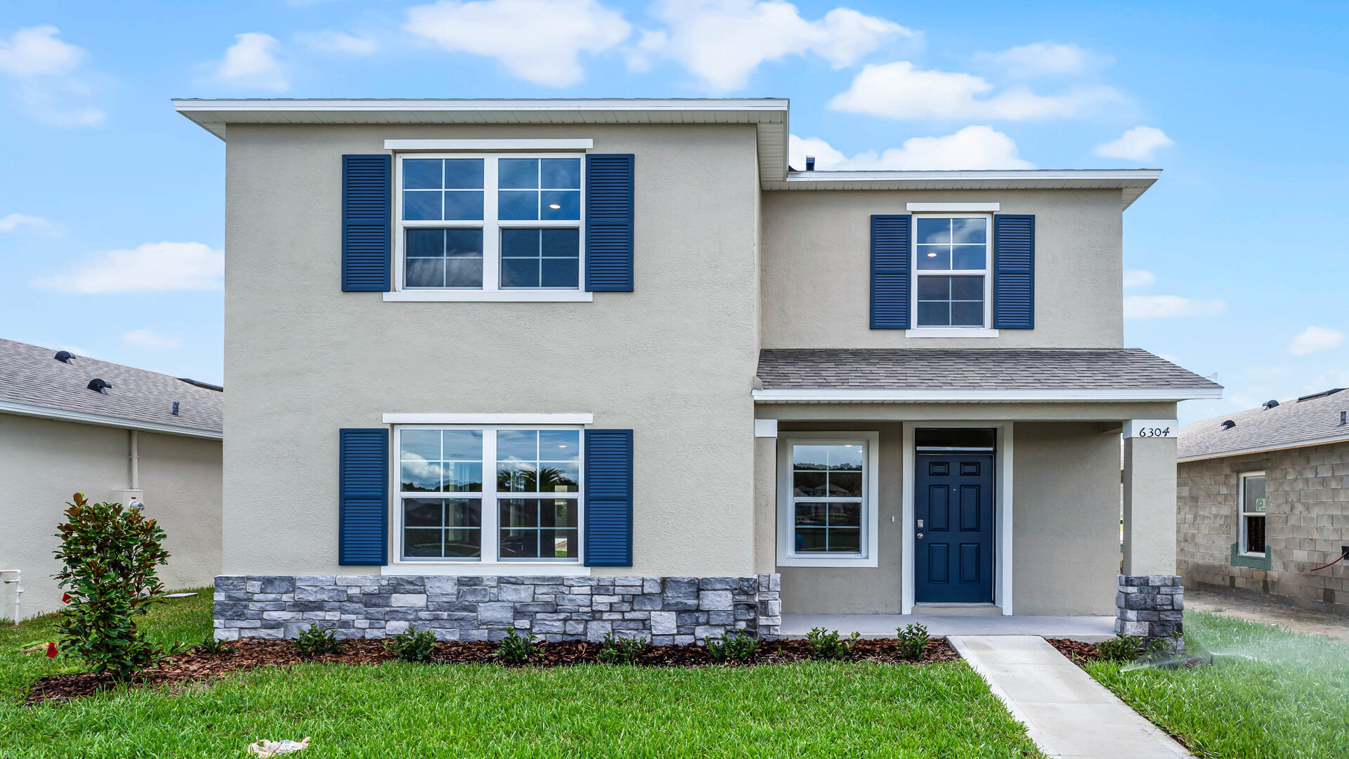 Two-story new home with large windows, and grassy front yard.