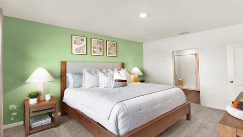 Spacious primary bedroom with king size bed, carpet flooring, natural lighting.